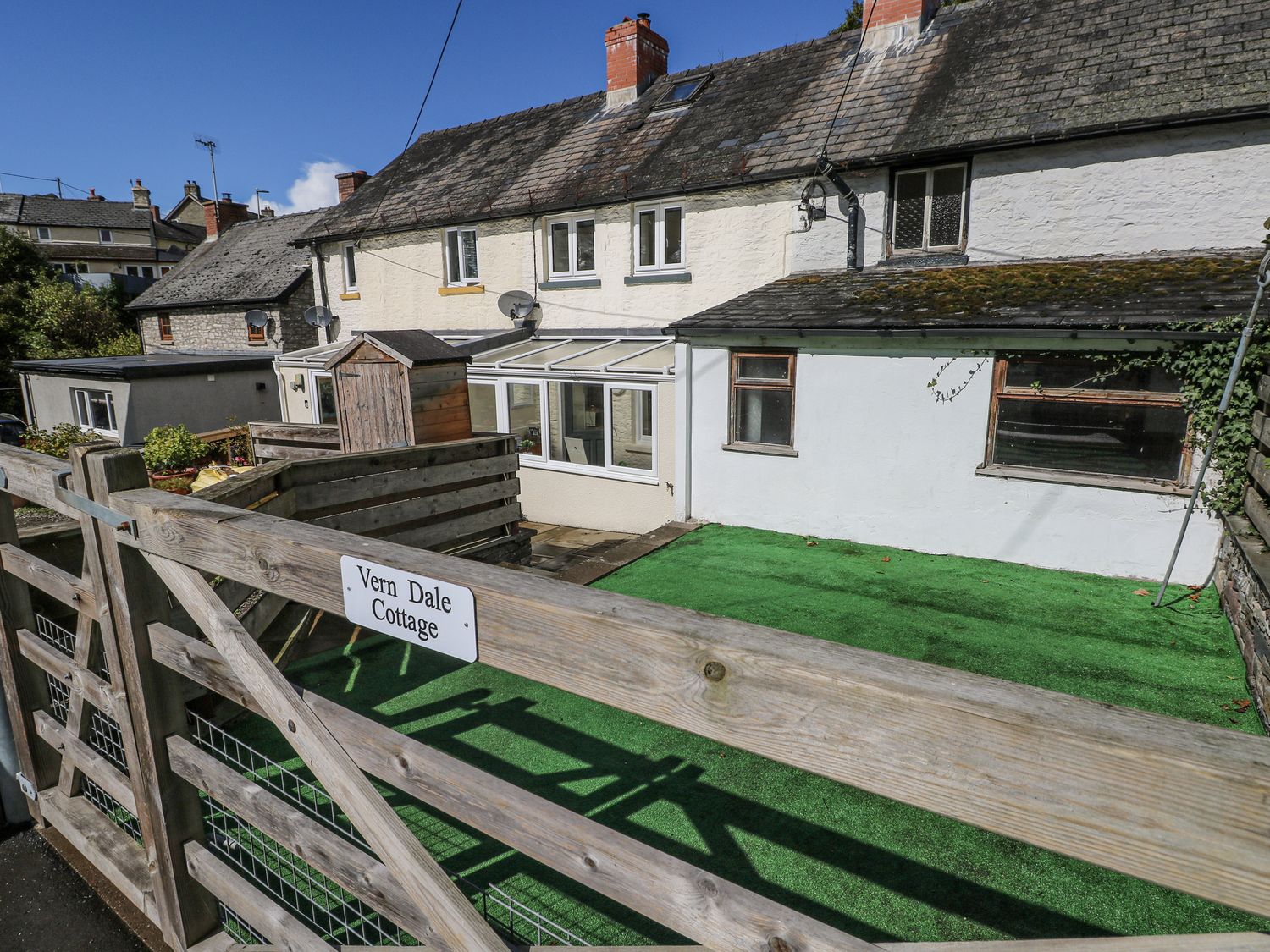 A garden with a fence and a conservatory at Vern Dale in Builth Wells