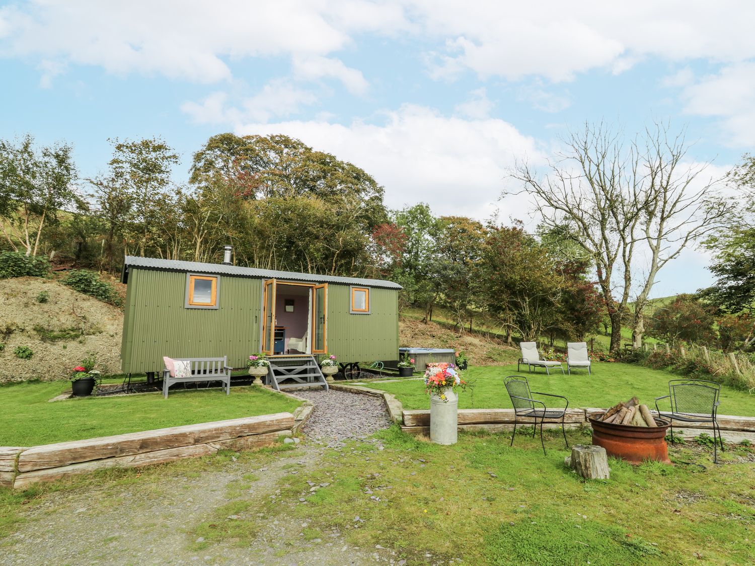 A shepherd's hut with outdoor seating and greenery at Brondel Luxury Shepherd's Hut in 