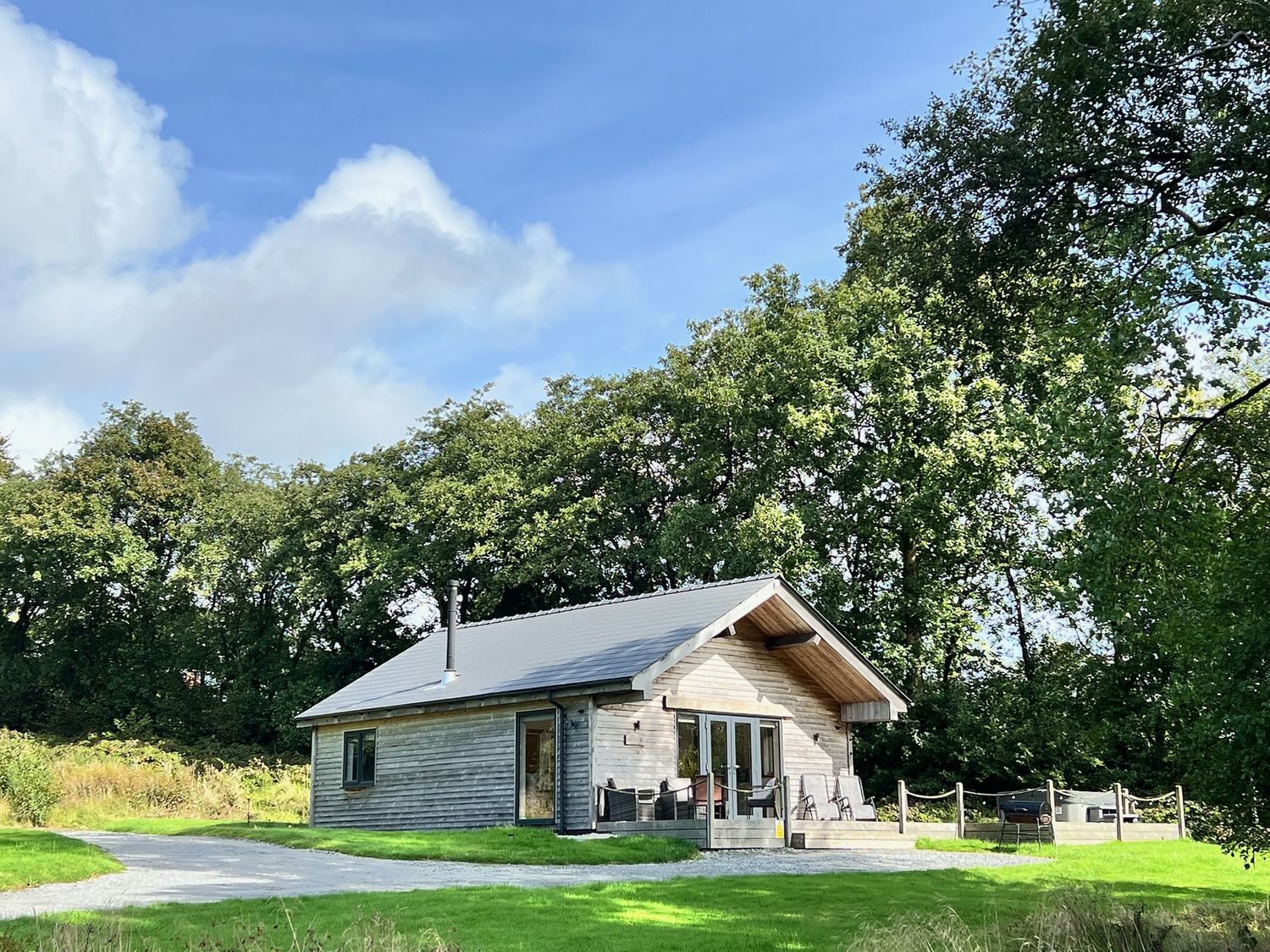 A cabin in the woods with a pathway and outdoor seating at Cadno Aber near Llanybydder