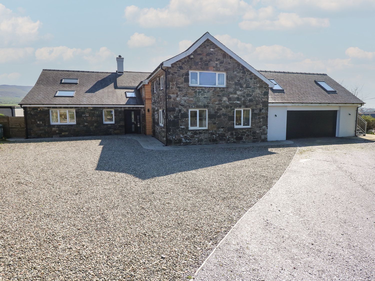 A house with a garage and gravel driveway at Criw Bryncroes near Sarn Meyllteyrn