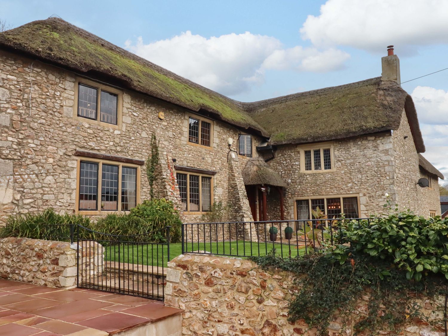 A house with a thatched roof and stone walls at Higher Wadden Farm in Southleigh