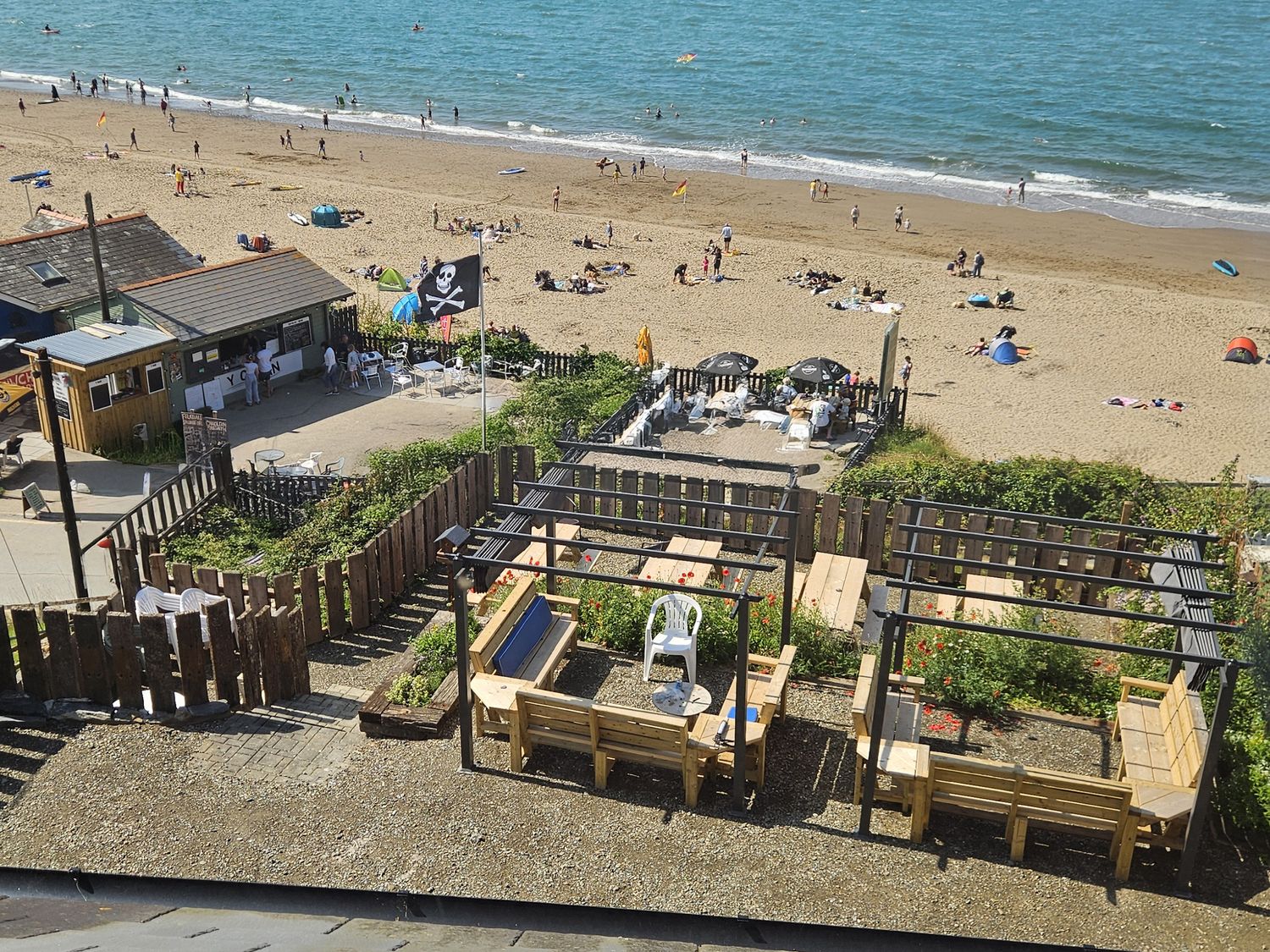 A beach scene with sun umbrellas and seating at Awel Deg in Cardigan