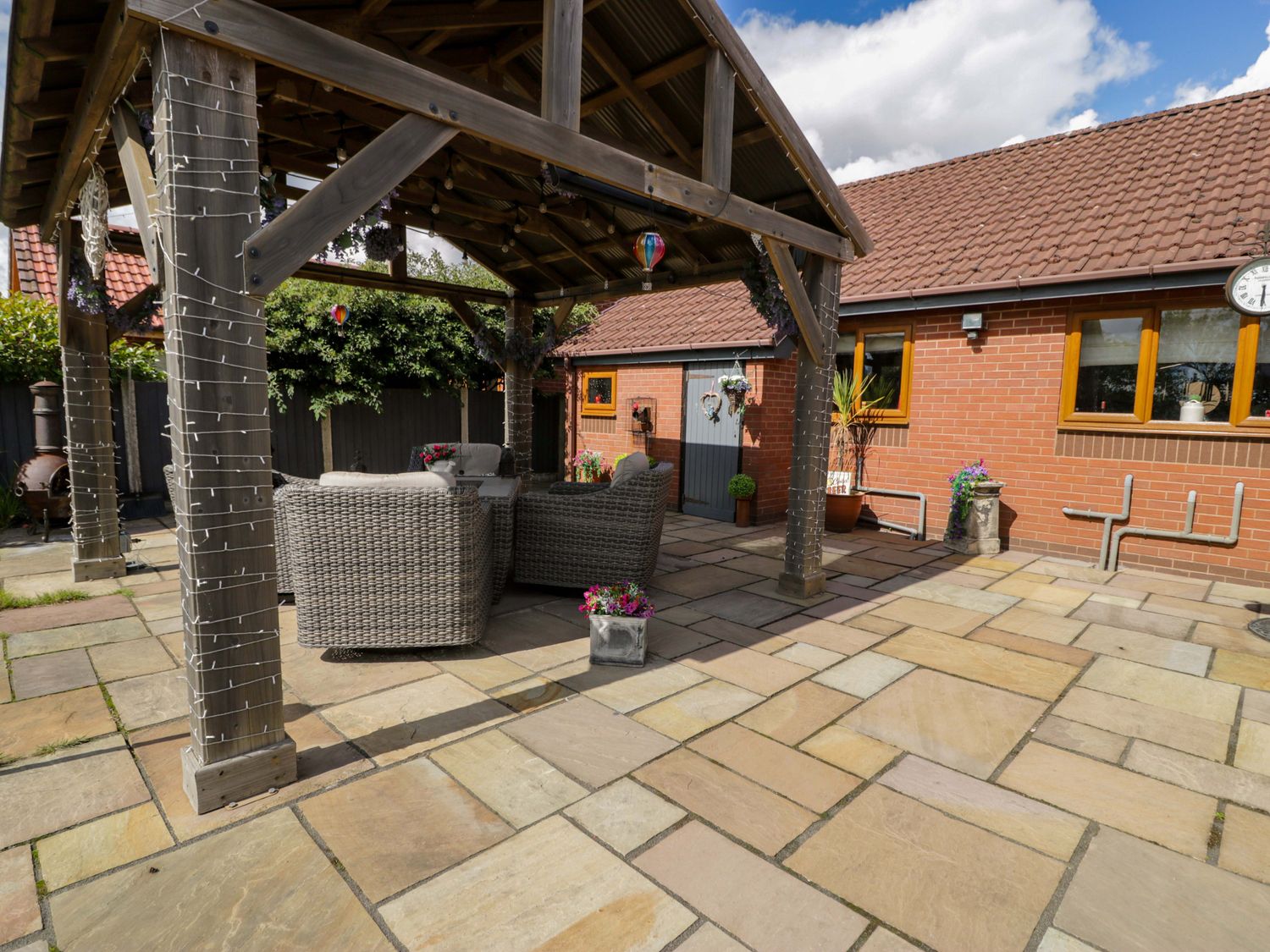 An outdoor patio area with wicker chairs and potted plants at Pentre Country Studio near Chirk
