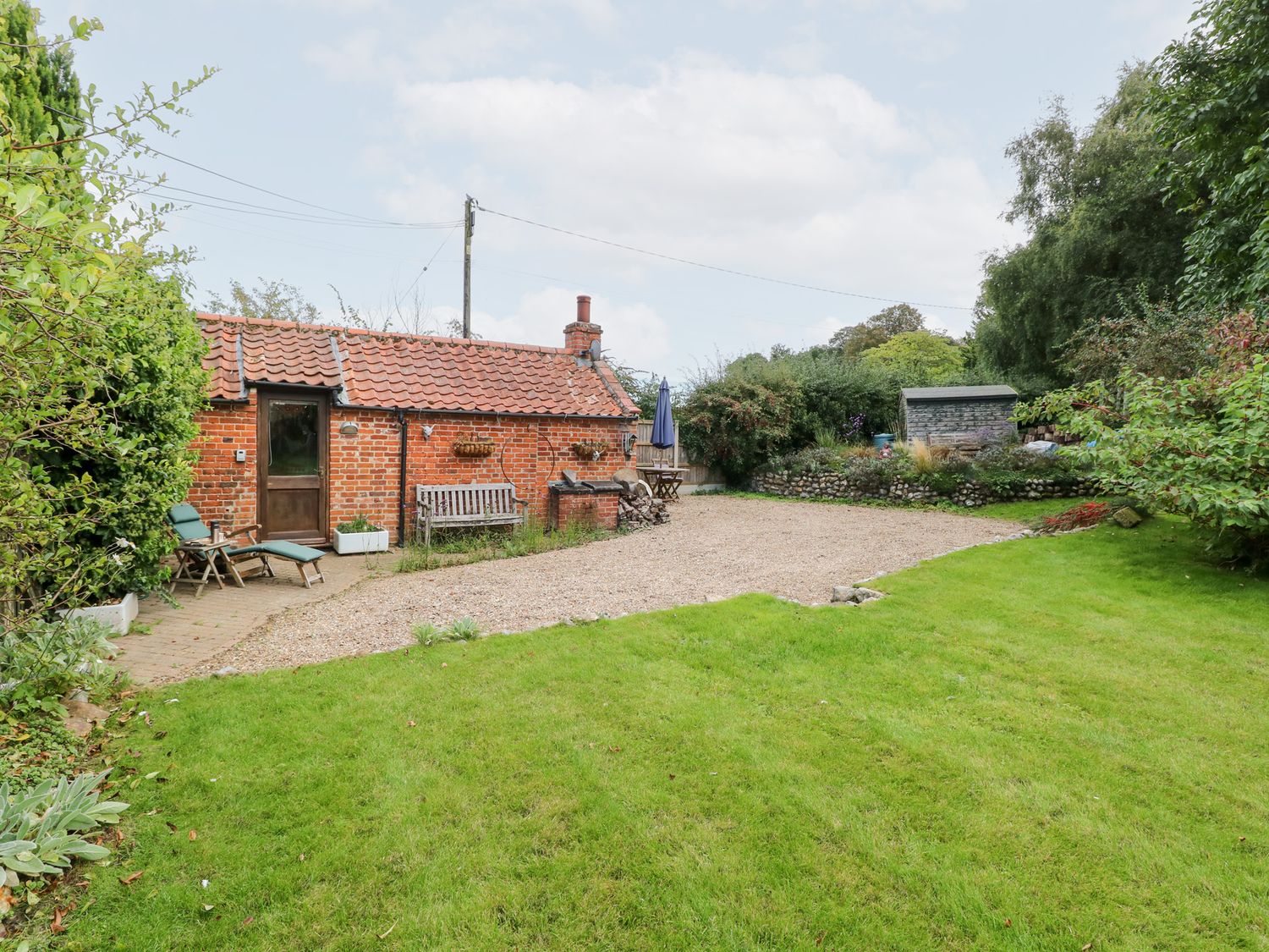 A garden with a cottage, benches, and table at The Retreat in Norwich