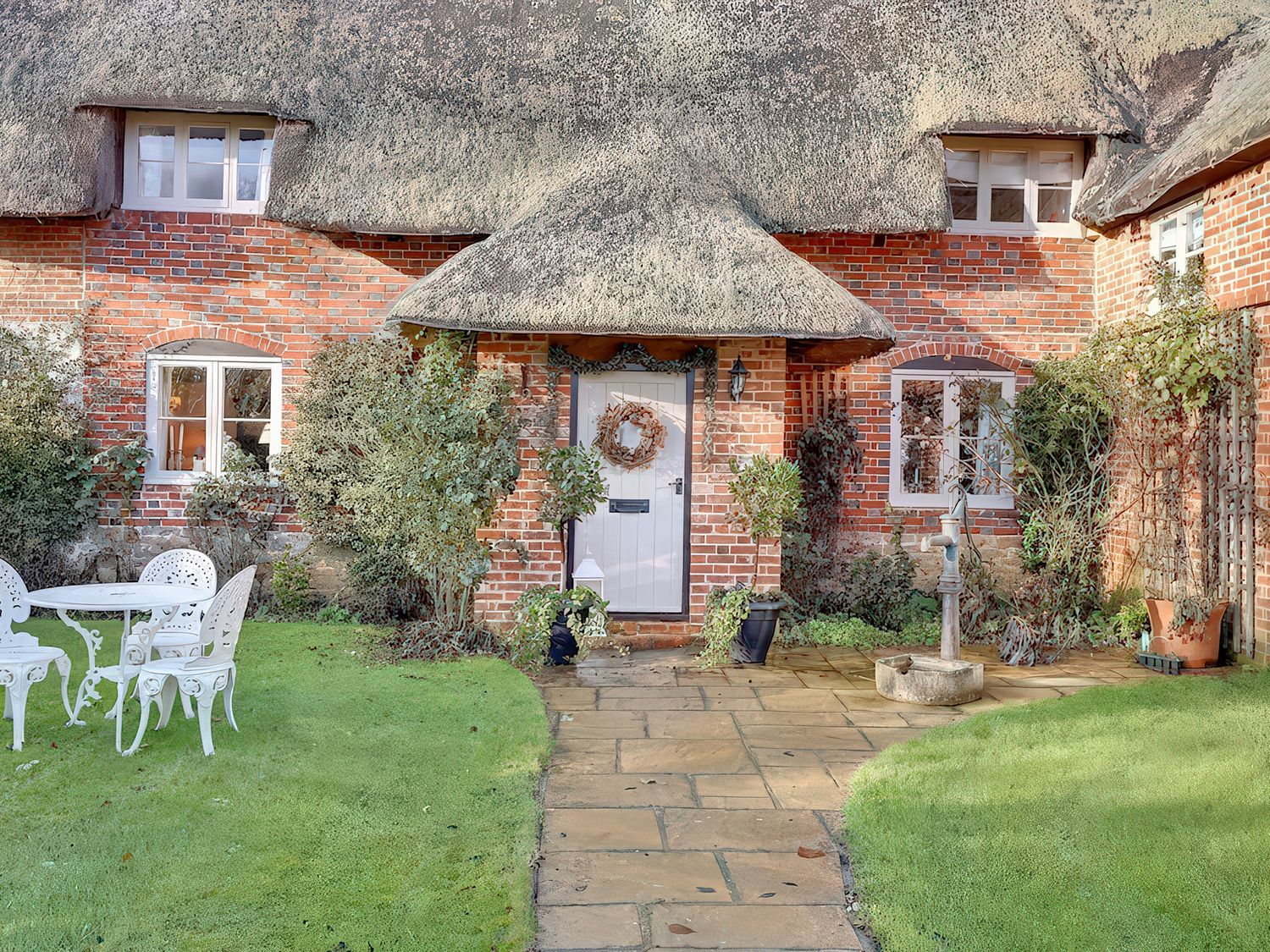 A garden with a table and chairs in front of the house at Lake Cottage in Swindon