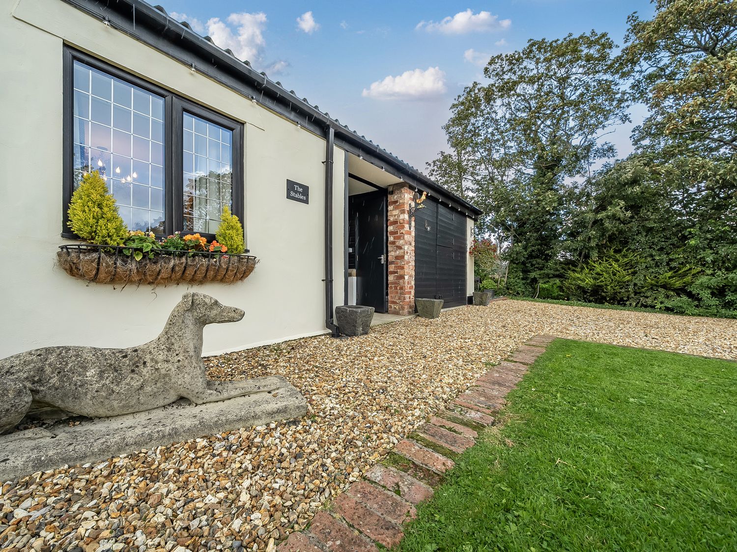 An outdoor view of a property entrance with a stone dog statue at The Stables in Poulton-le-Fylde