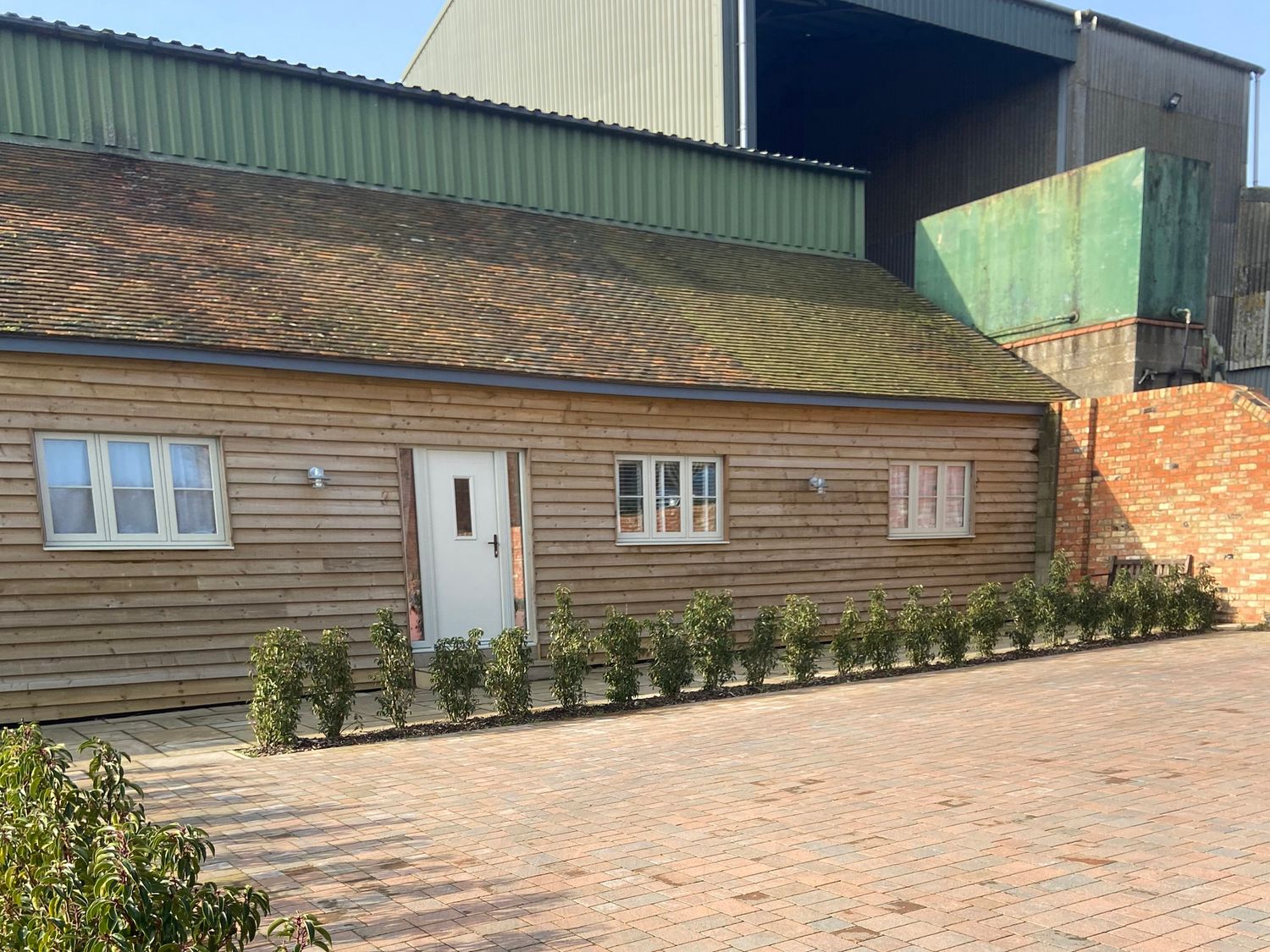 A wooden building with windows and door at The Cart Shed in Bedford