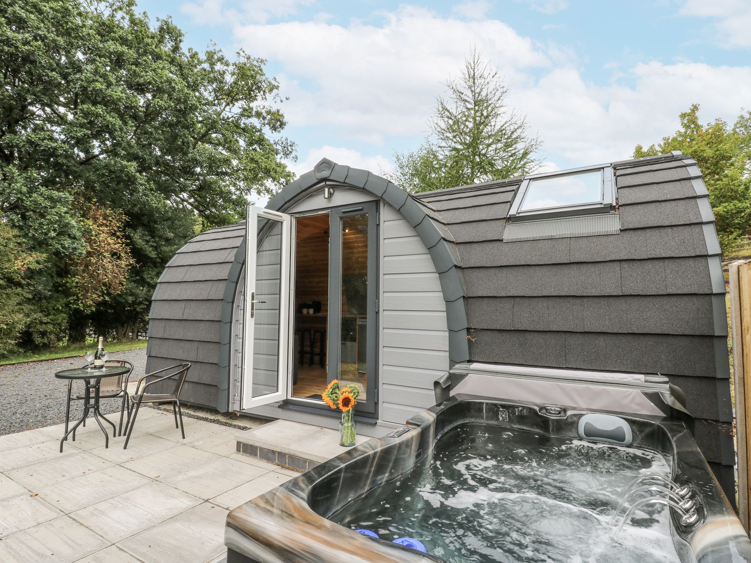 A hot tub and seating area outside a modern structure at Oak View in Rhayader