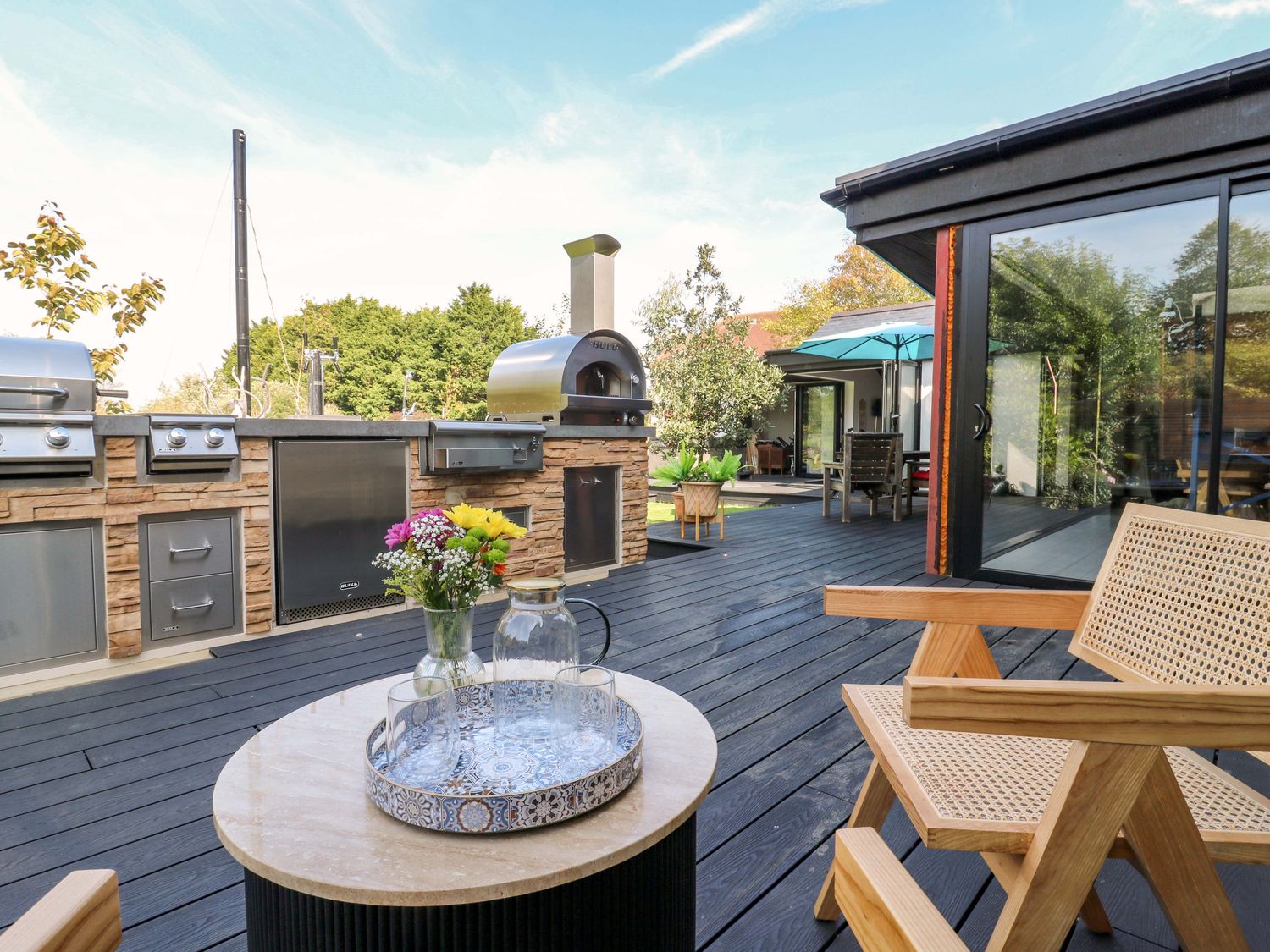An outdoor dining area with a grill and seating at Manor Farm House in Merton near Bicester