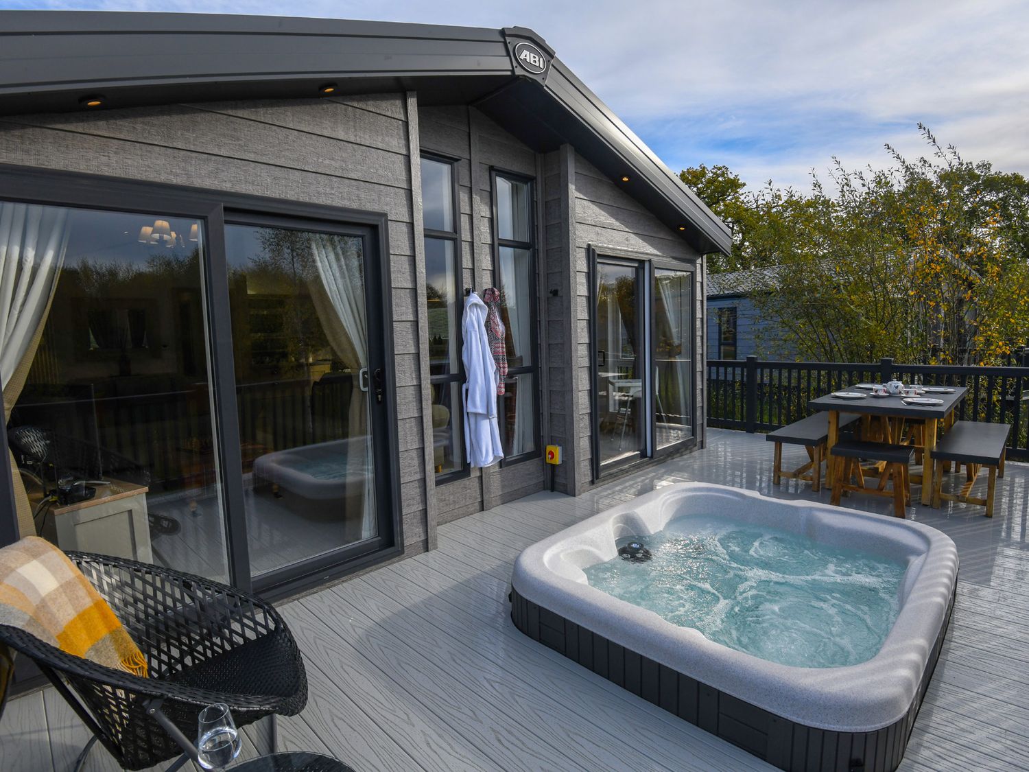 An outdoor terrace with a hot tub and dining table at Lakewood Retreat Woodhall Spa