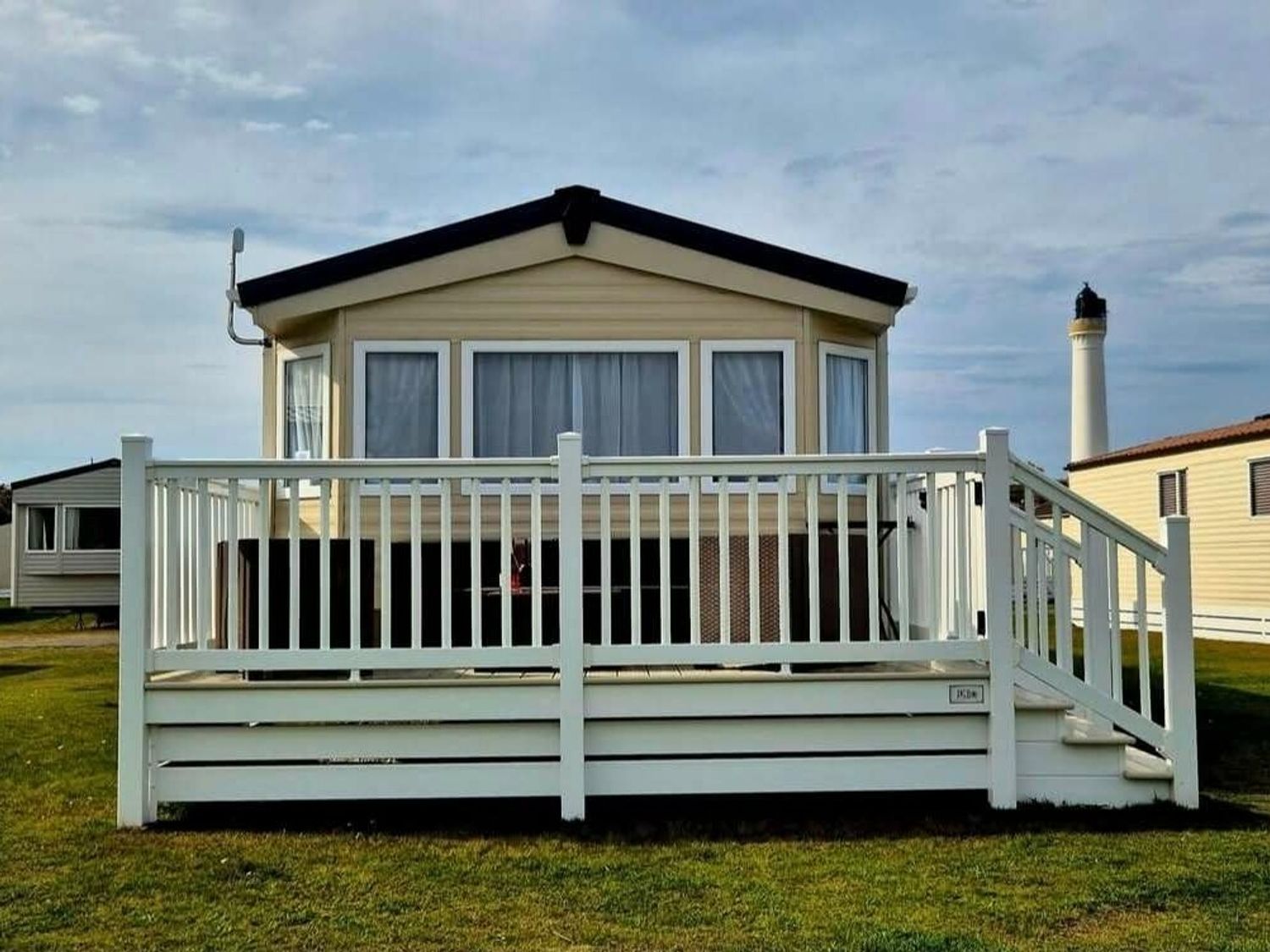 a holiday home with a deck and sliding glass doors at Silver Sands Holiday Park - Holiday Accommodation 11481 in Lossiemouth