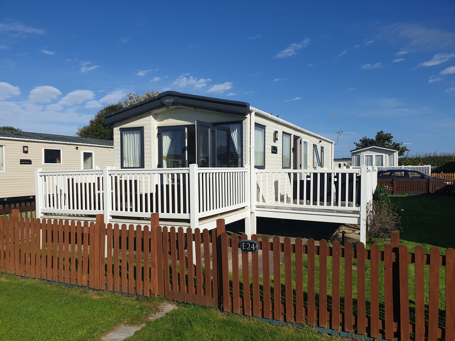 A mobile home with a deck and fence at Unity Holiday Resort - Holiday Accommodation 16507, Brean, Somerset, United Kingdom