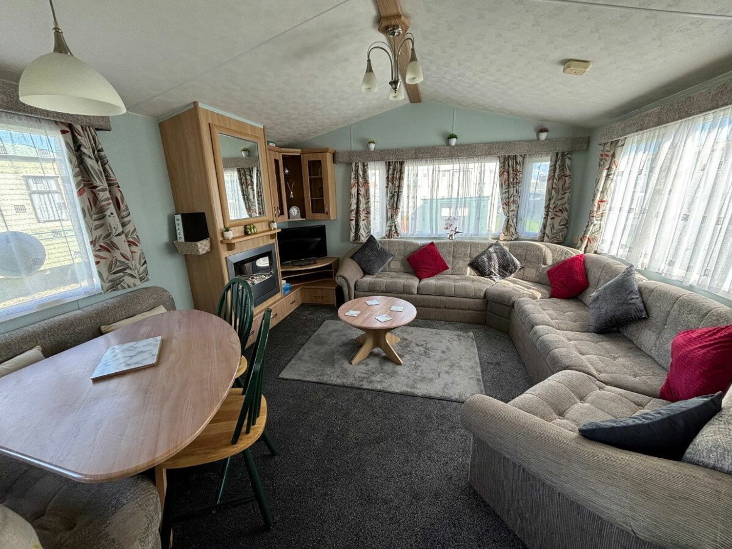 a lounge area with a curved sofa and a circular dining table at Coral Beach - Holiday Accommodation 16858 in Ingoldmells