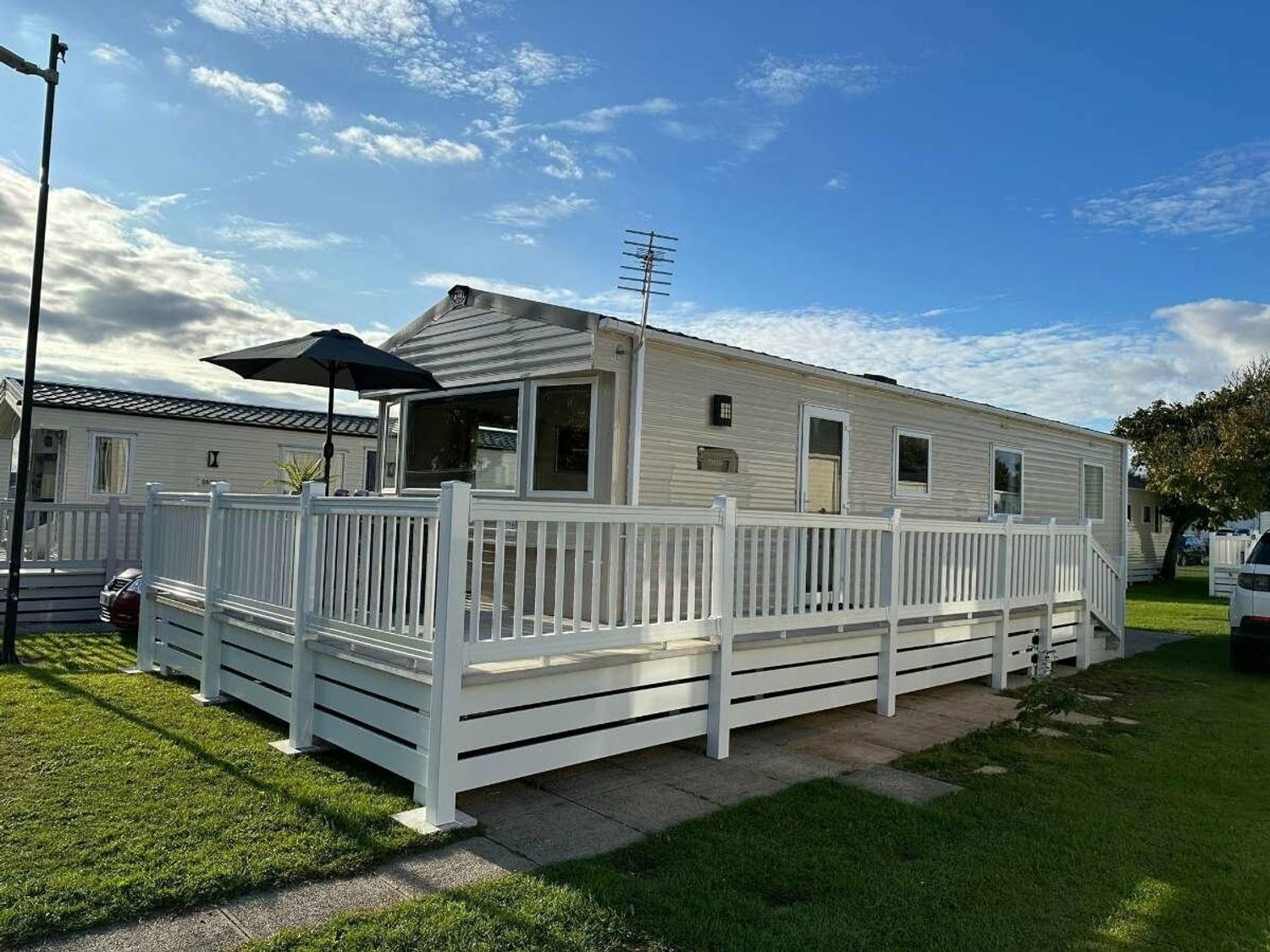 a mobile home with a deck and an umbrella at Shorefield Country Park - Holiday Accommodation 18837 Lymington
