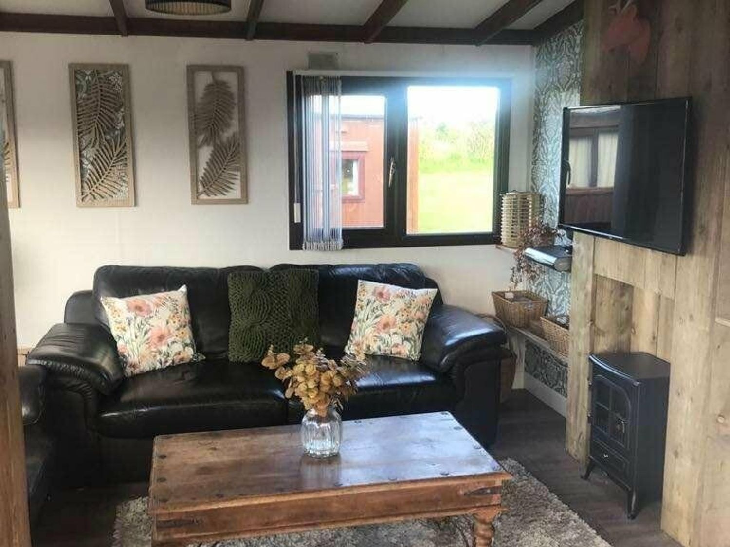 a living room with a black sofa, wooden coffee table, and window at Hafan y Mor Haven - Holiday Accommodation 20258, Pwllheli