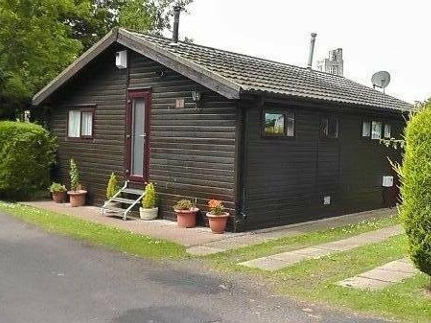a wooden chalet with a porch and planters at Haggerston Castle - Holiday Accommodation 3441 in Berwick-upon-Tweed