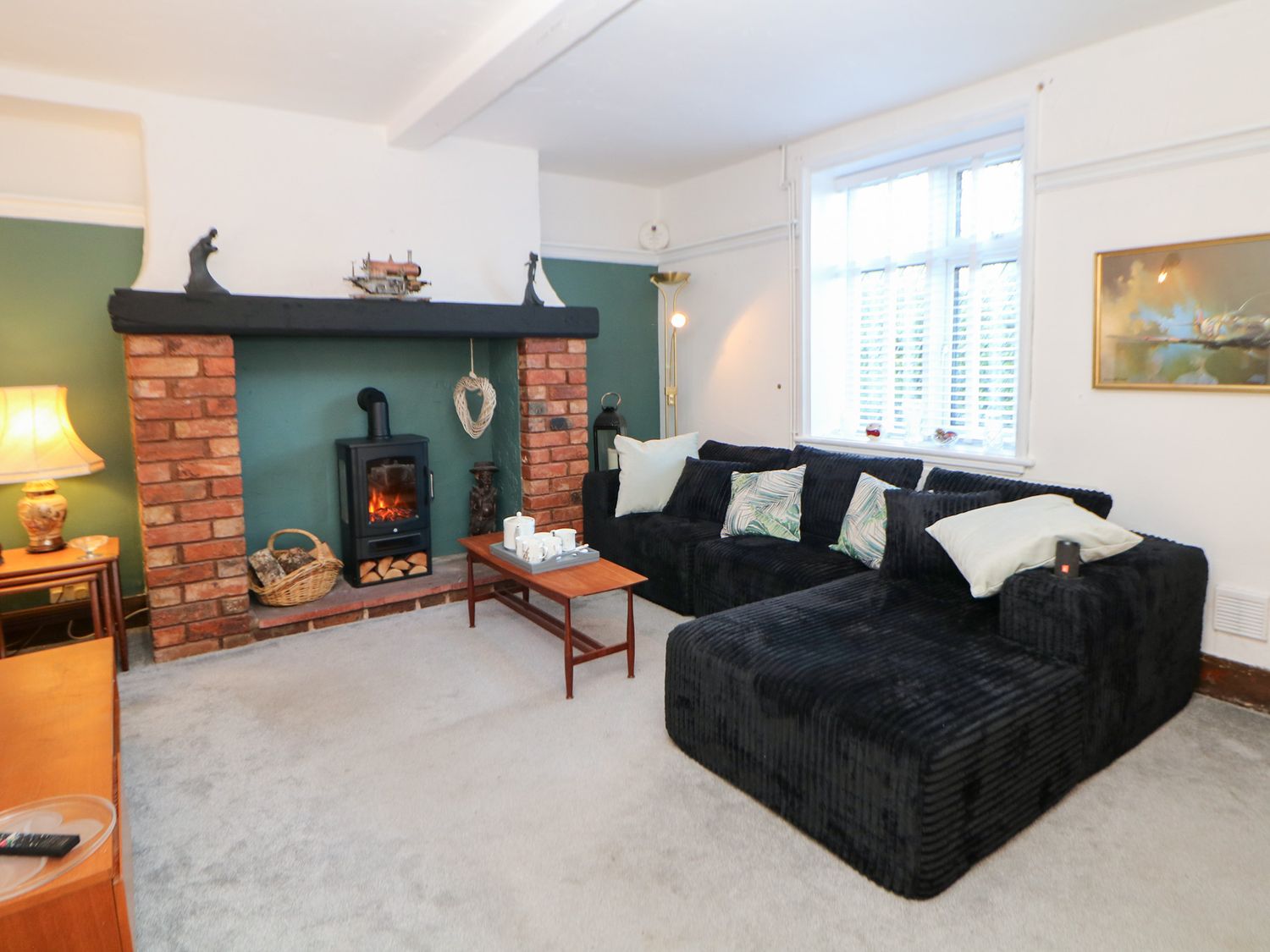 A living room with a black sofa and a fireplace at Shunter’s Nook in Colwich