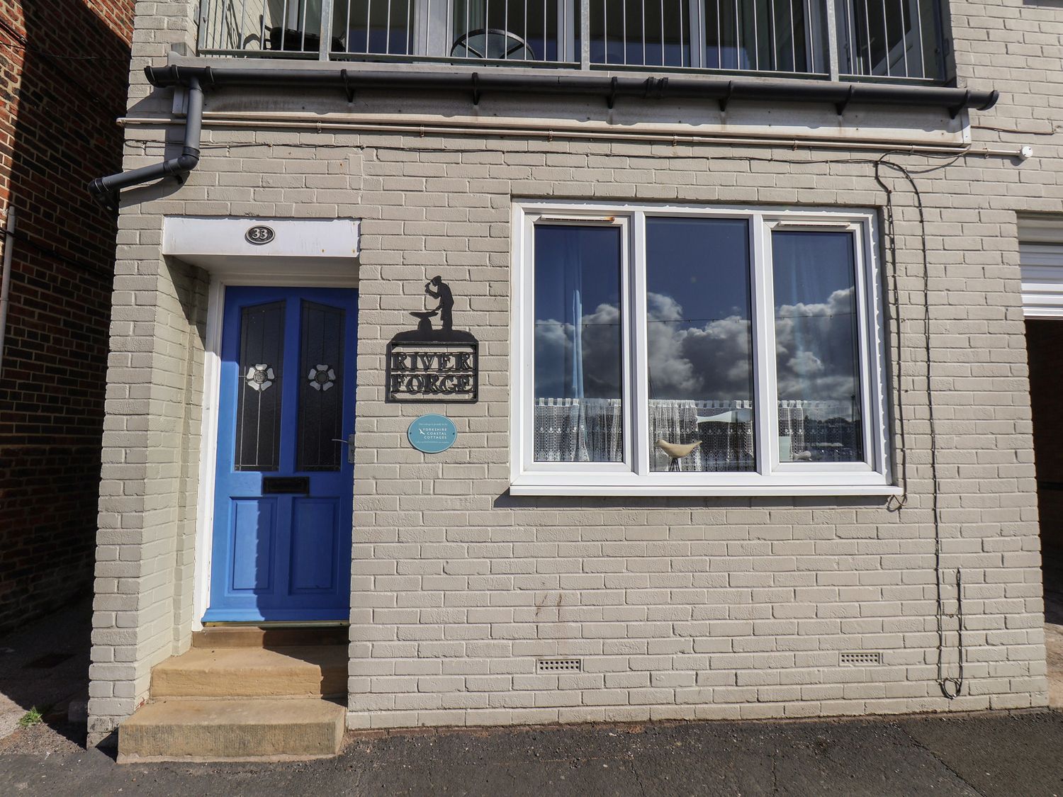 An exterior view with a blue door, window, and sign at Farriers Yard in Whitby