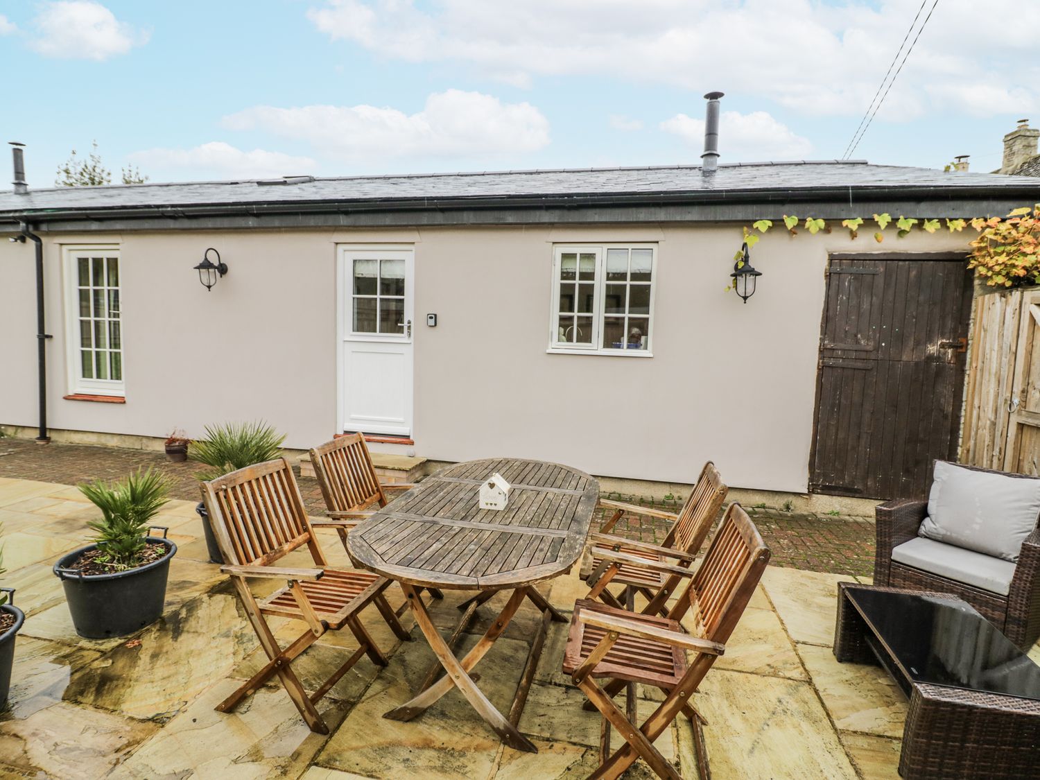 A garden with a wooden table and chairs at Lily Stables in Black Bourton near Bampton, Oxfordshire