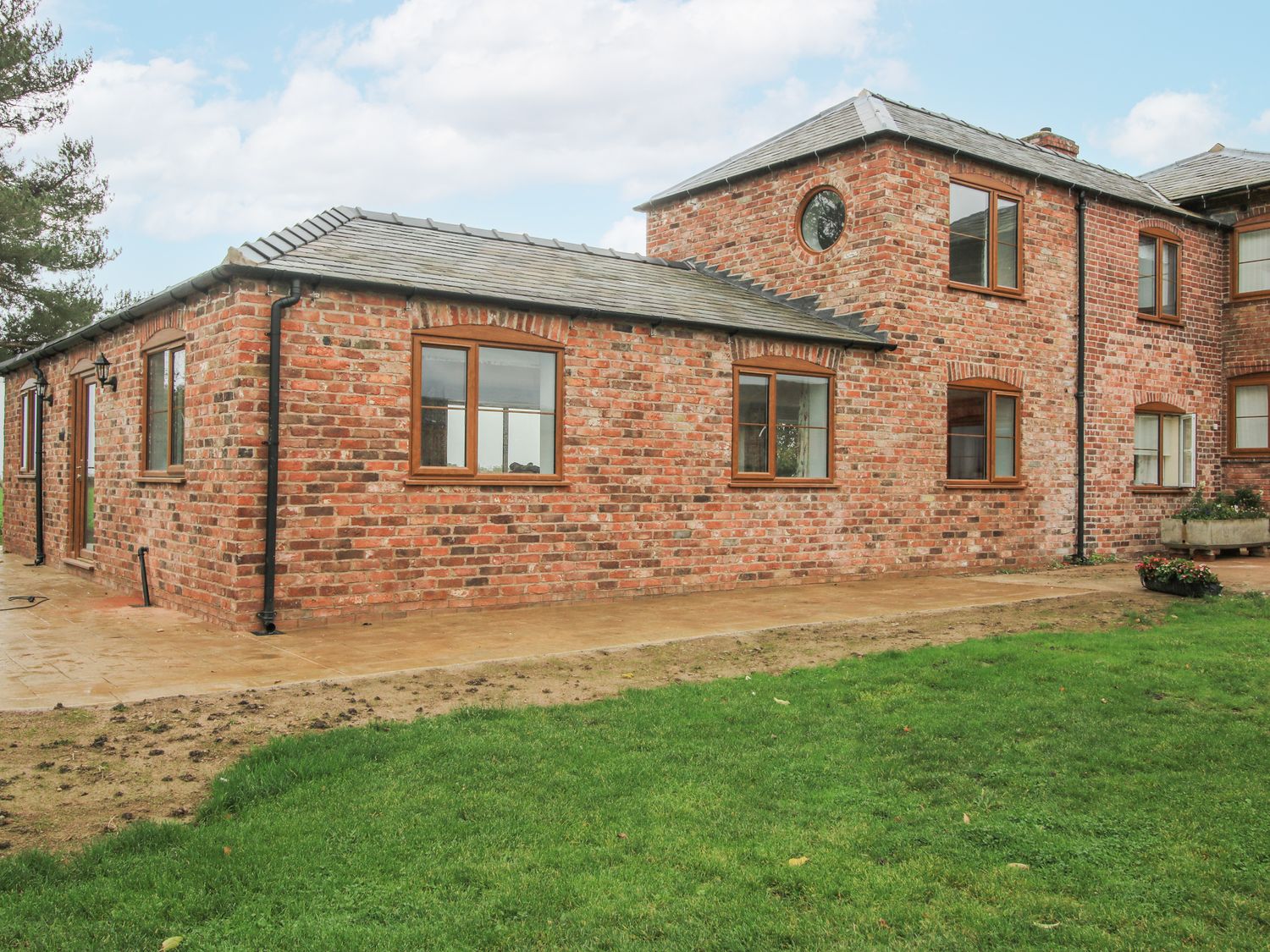 An exterior view of a brick house with a garden at Garden Cottage in Ellesmere