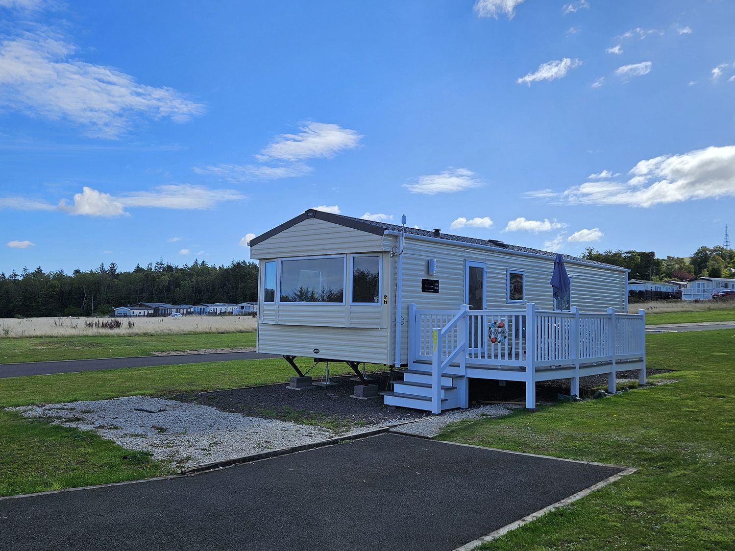 A caravan with a deck and steps at Thurston Manor Caravan Park, Pony Meadow, Dunbar