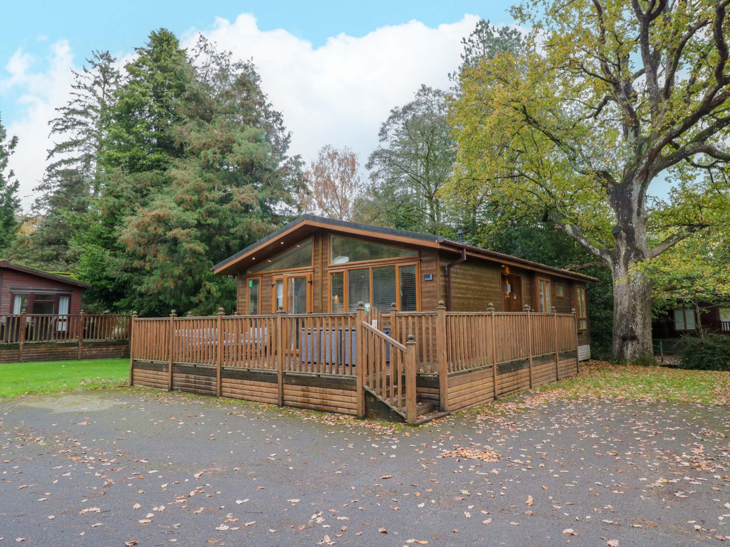 A wooden cabin with a deck in an outdoor area at 5 Waterside Wood Troutbeck Bridge
