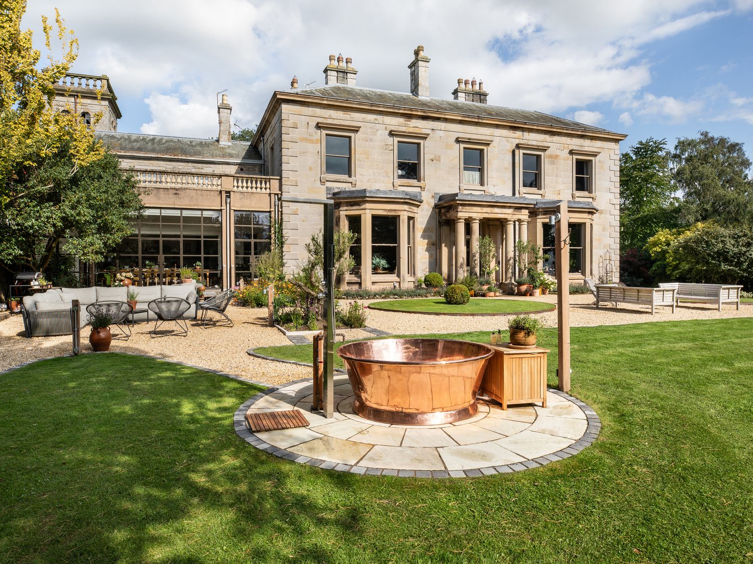 A garden with a copper bathtub and outdoor seating at The Country House Cumbria Castle Carrock