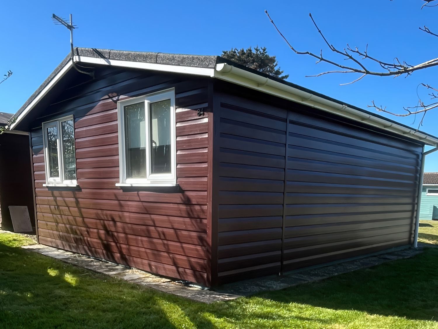 A wooden shed with windows and a pathway at Stanbury