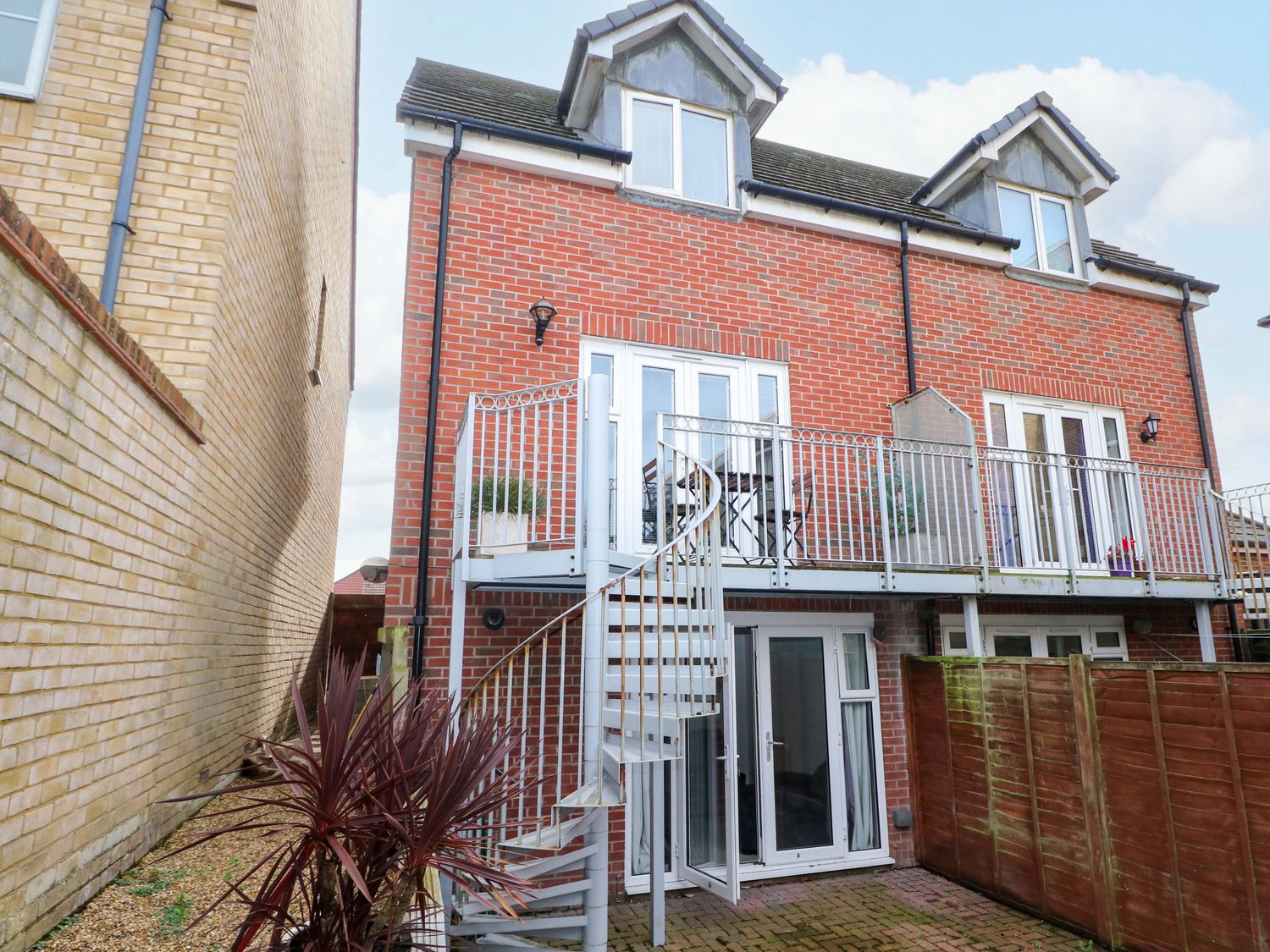 An outdoor view of a house with balcony and spiral stairs at 67a Harbour Way Shoreham-by-Sea