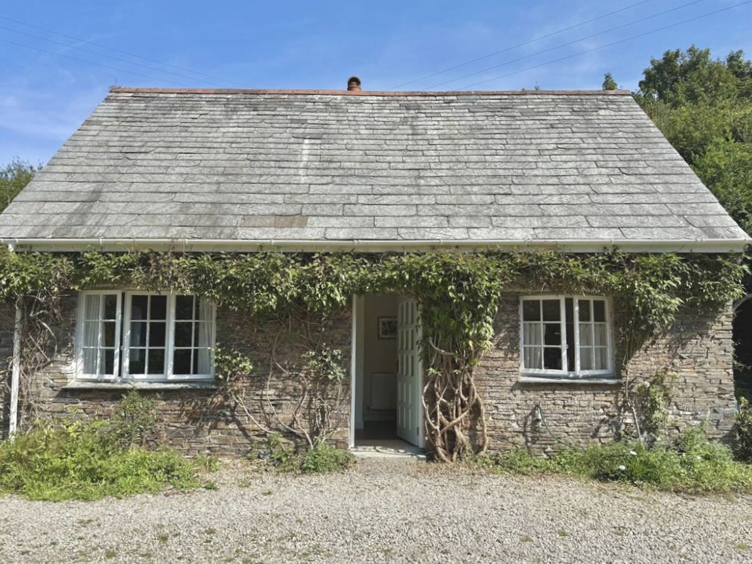 A cottage with a gravel pathway and ivy at Copper Mine Cottage in Trelill near Port Isaac