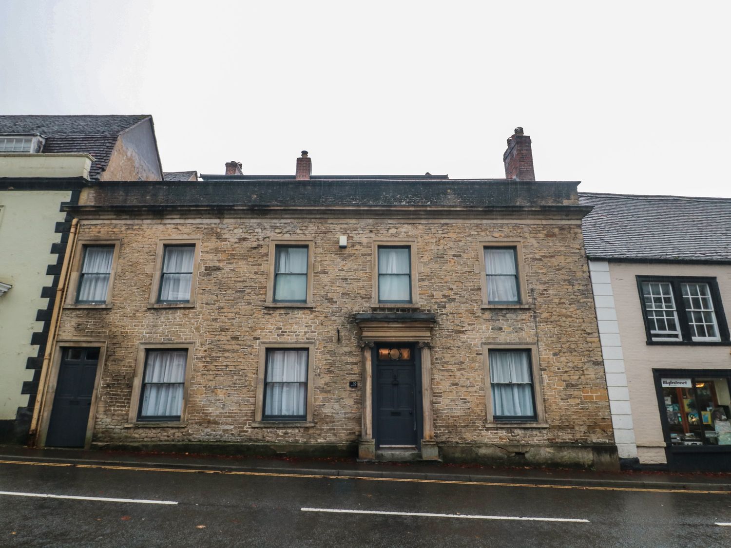 A brick building with windows and a door on a street at ASH HOUSE
