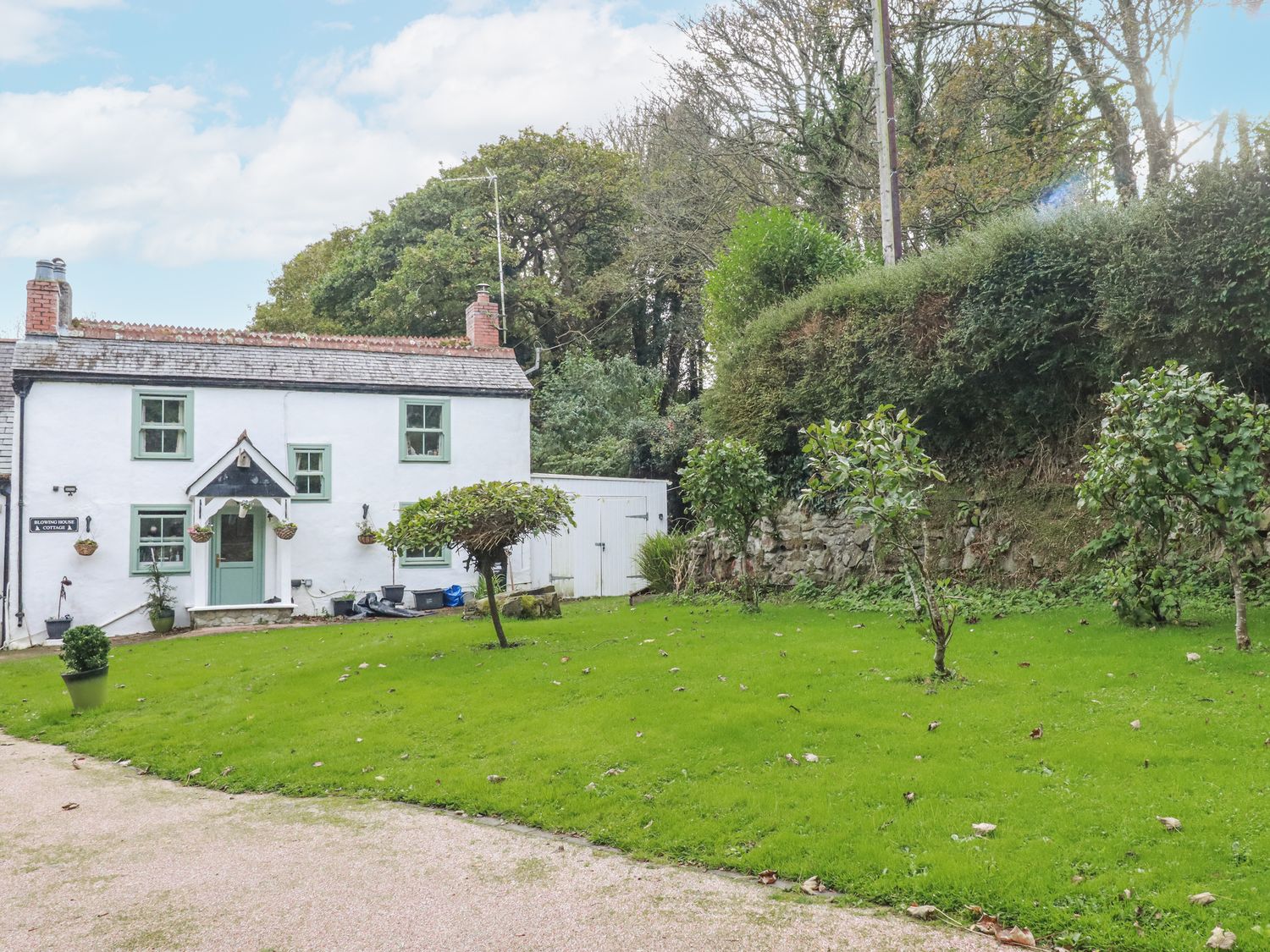 A cottage with a garden and trees at Blowing House Cottage in Perranporth