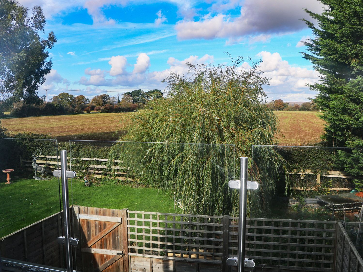 A garden view with a fence and tree at No 1 The Crickets in Bognor Regis