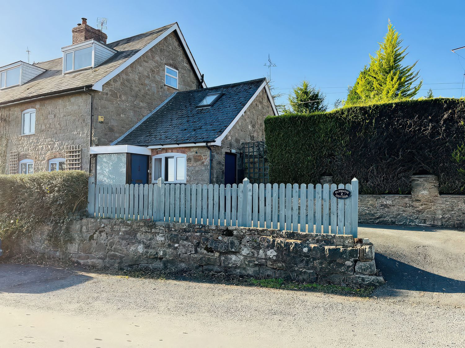 A house with a fence and hedge at Bumble Bee at 2 Clematis Cottage near Clee Hill