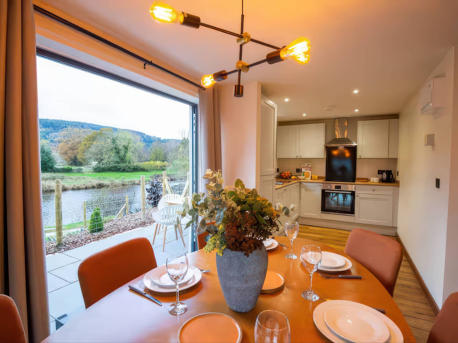 A dining room with a table set near a kitchen at Mountain View Cottage in Llanrwst