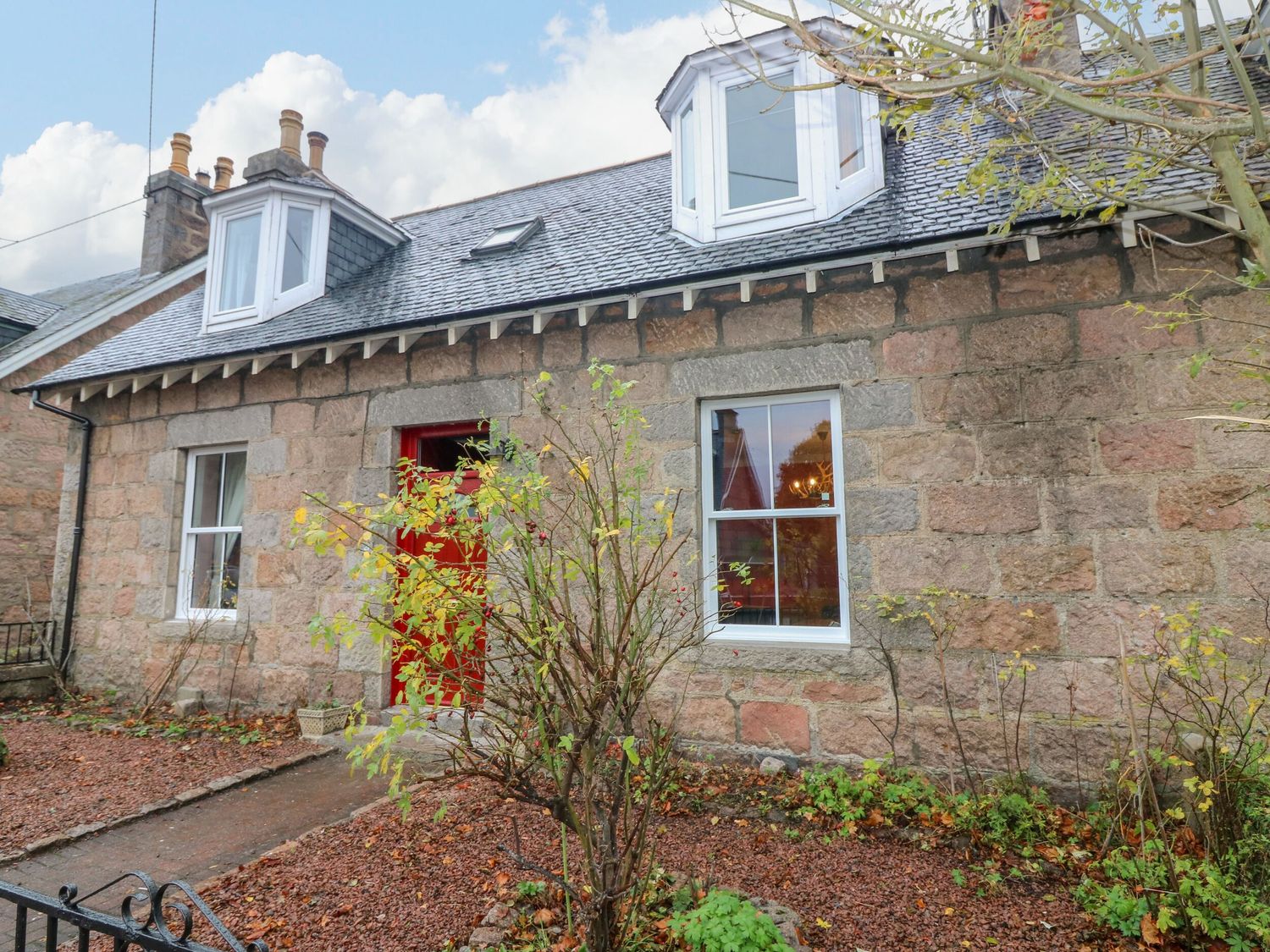 A house with stone walls and a red door at Lindean in Ballater