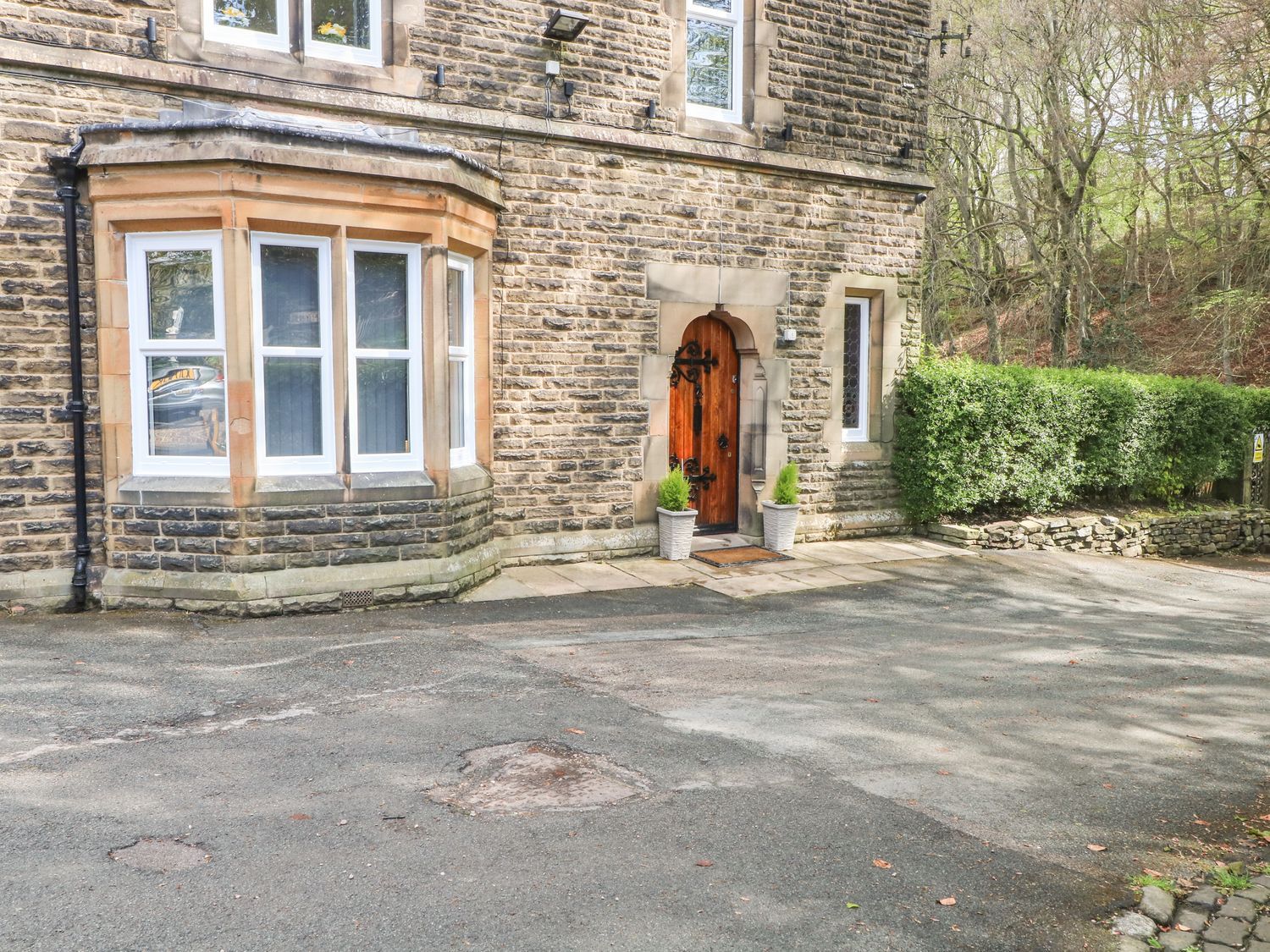 An outdoor entrance with stone walls and potted plants at Beechwood House Hadfield