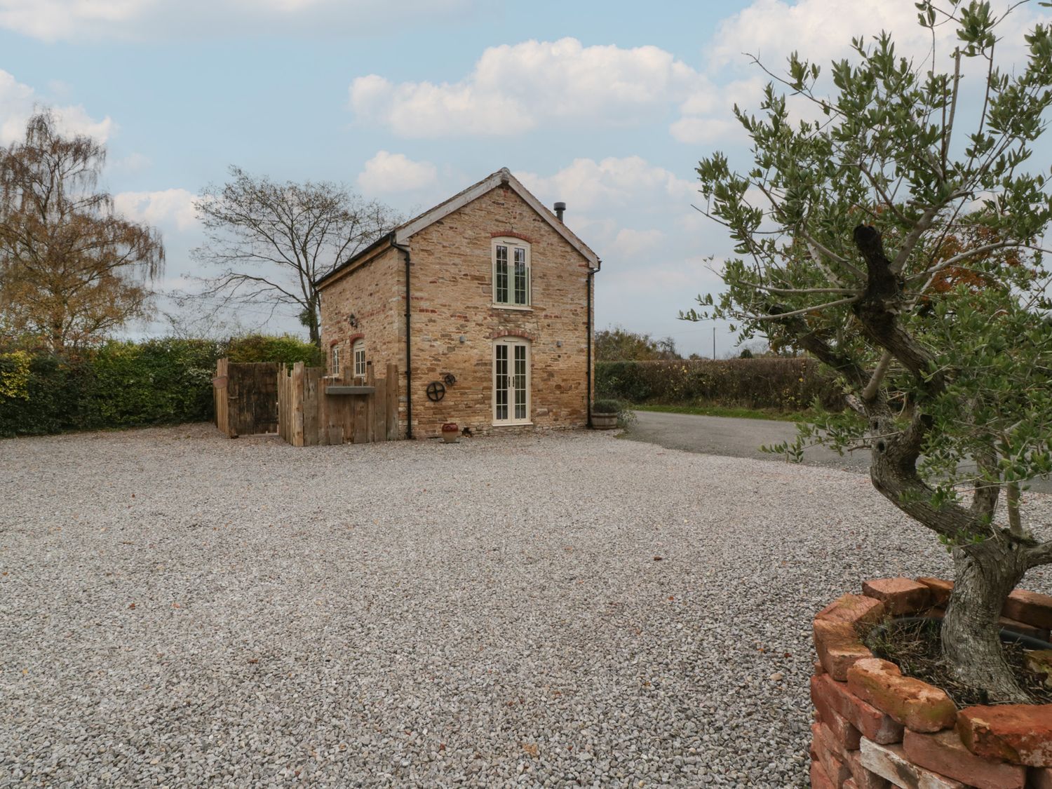 A house with a gravel area and greenery at The Cow Shed in Ross-on-Wye