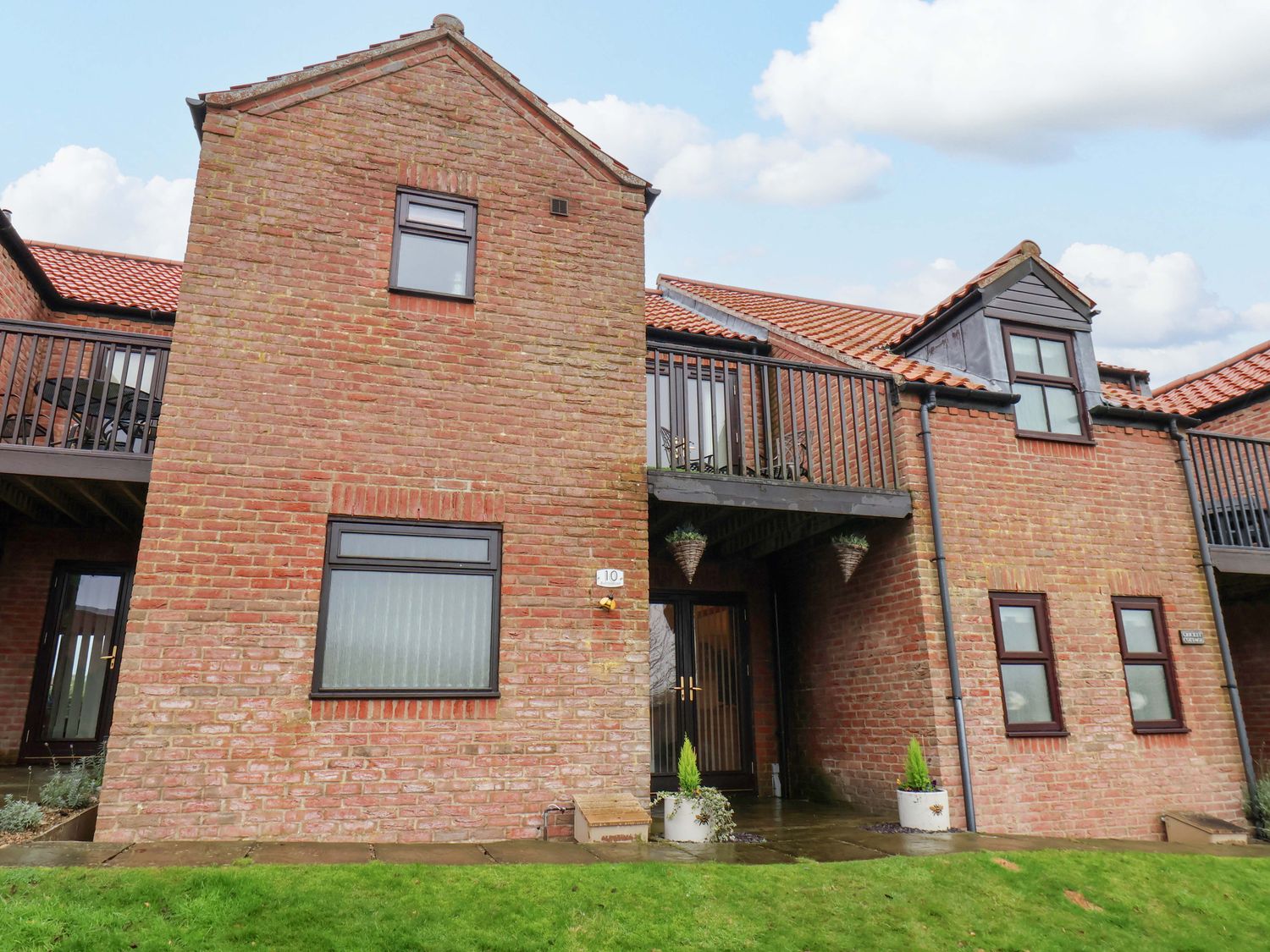 A brick building with a balcony and garden area at Bumblebee Cottage in Whitby