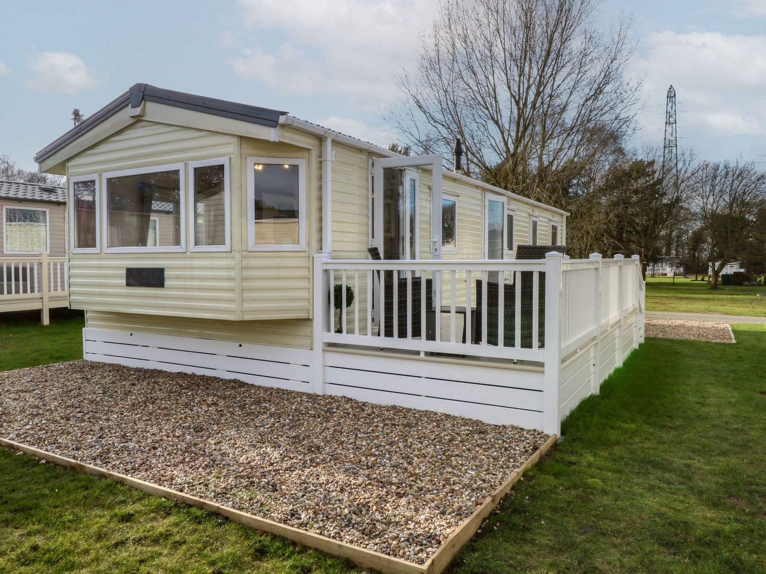 A caravan with a wooden deck and gravel area at 46 Foxburrow Hang in Great Yarmouth