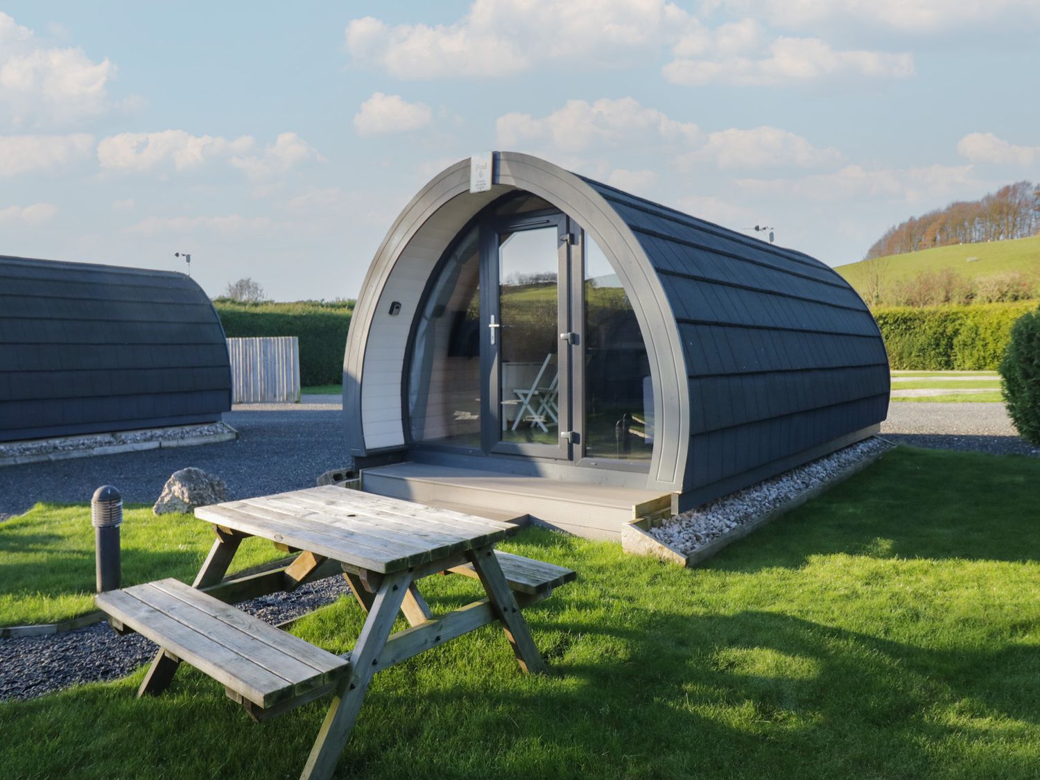 A pod with a table and benches in an outdoor area at Pod 6 (No Pets) in Tewitfield