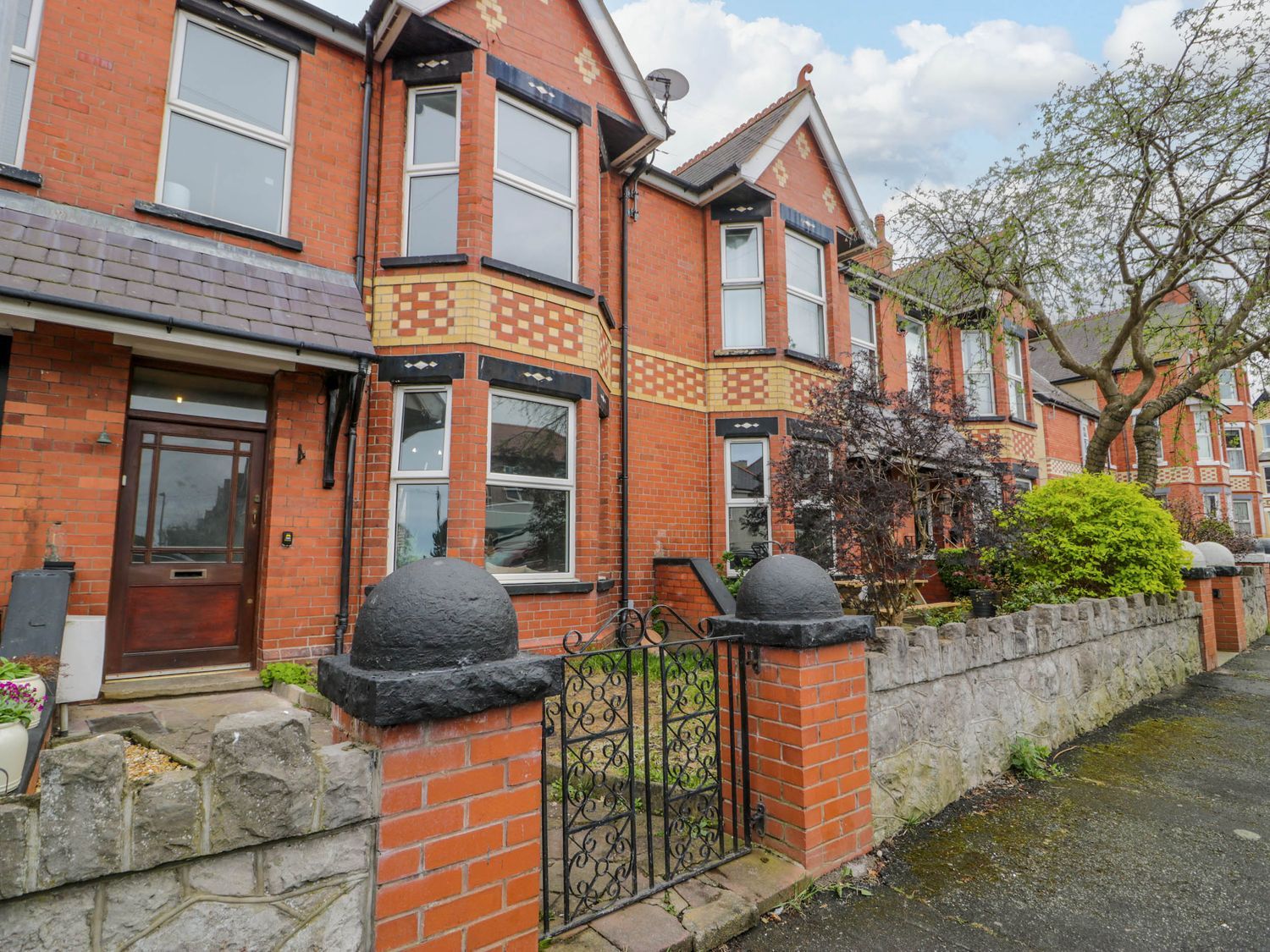 A brick house with a gate and stone wall at Canning Lodge in Colwyn Bay