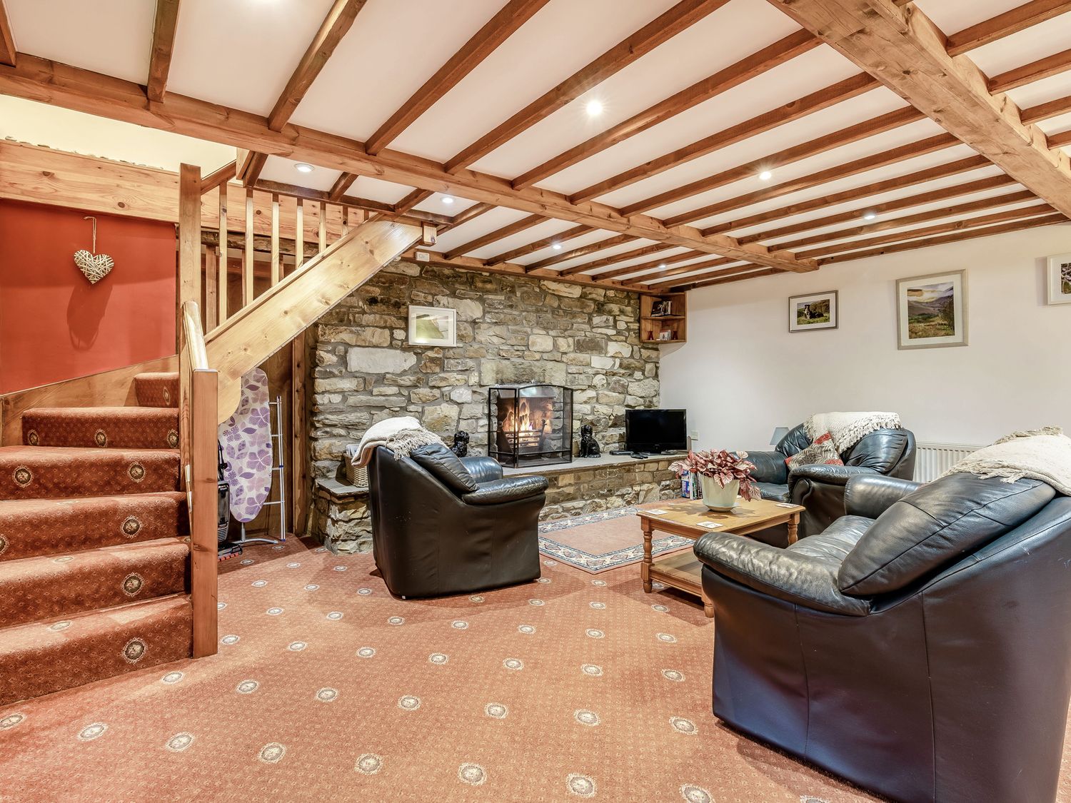 A living room with leather sofas a wooden coffee table a stone fireplace and wooden beams at Brant View in Cautley near Sedbergh