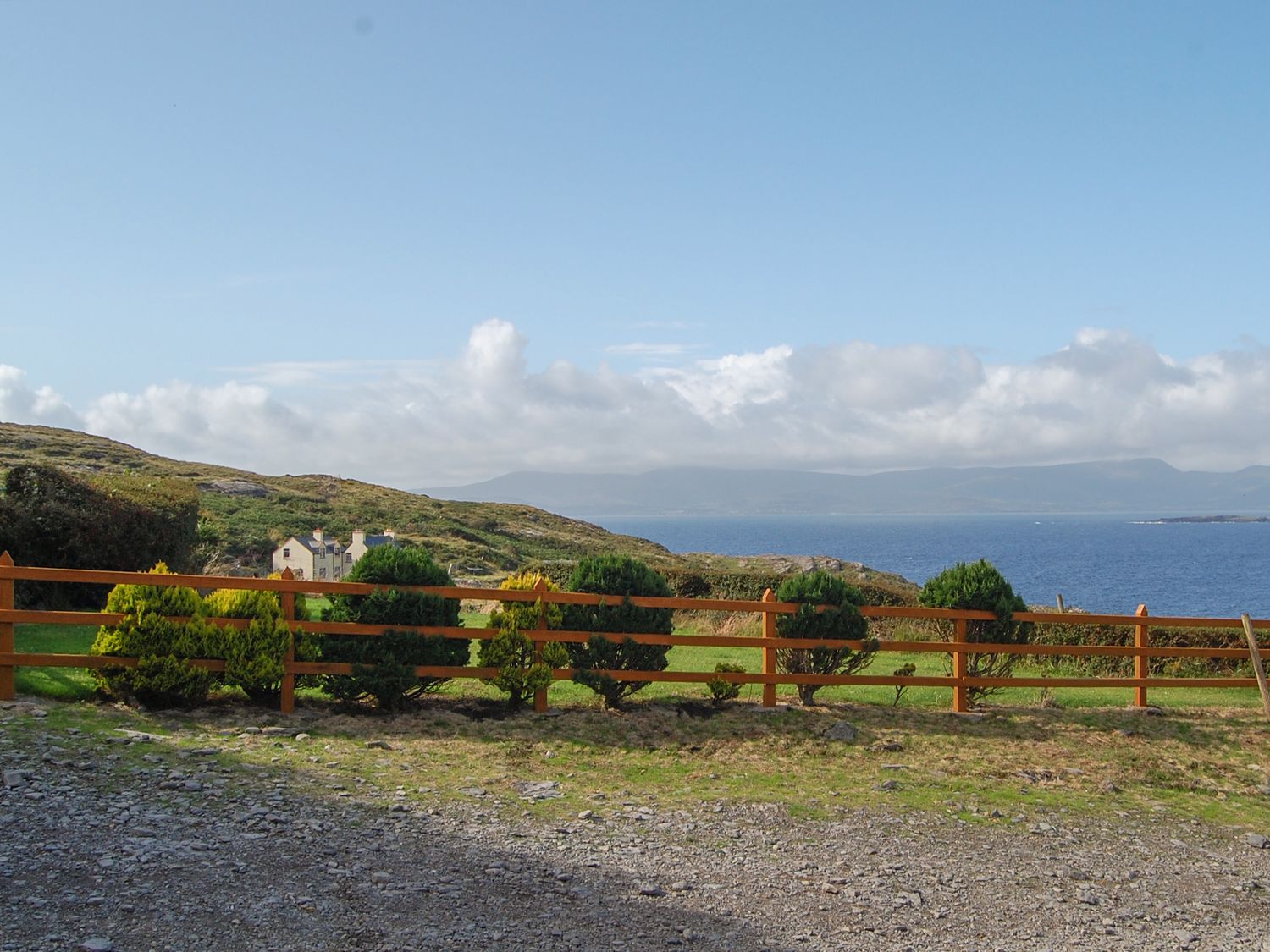 A coastal landscape with a brown wooden fence and bushes overlooking the ocean at Nana's House in Allihies County Cork