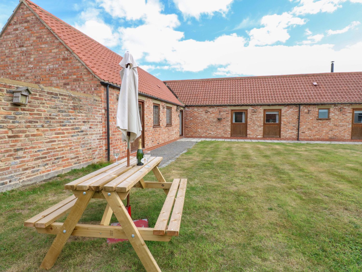 A picnic table with an umbrella in the garden at Cooper Cottage in Potto near Stokesley