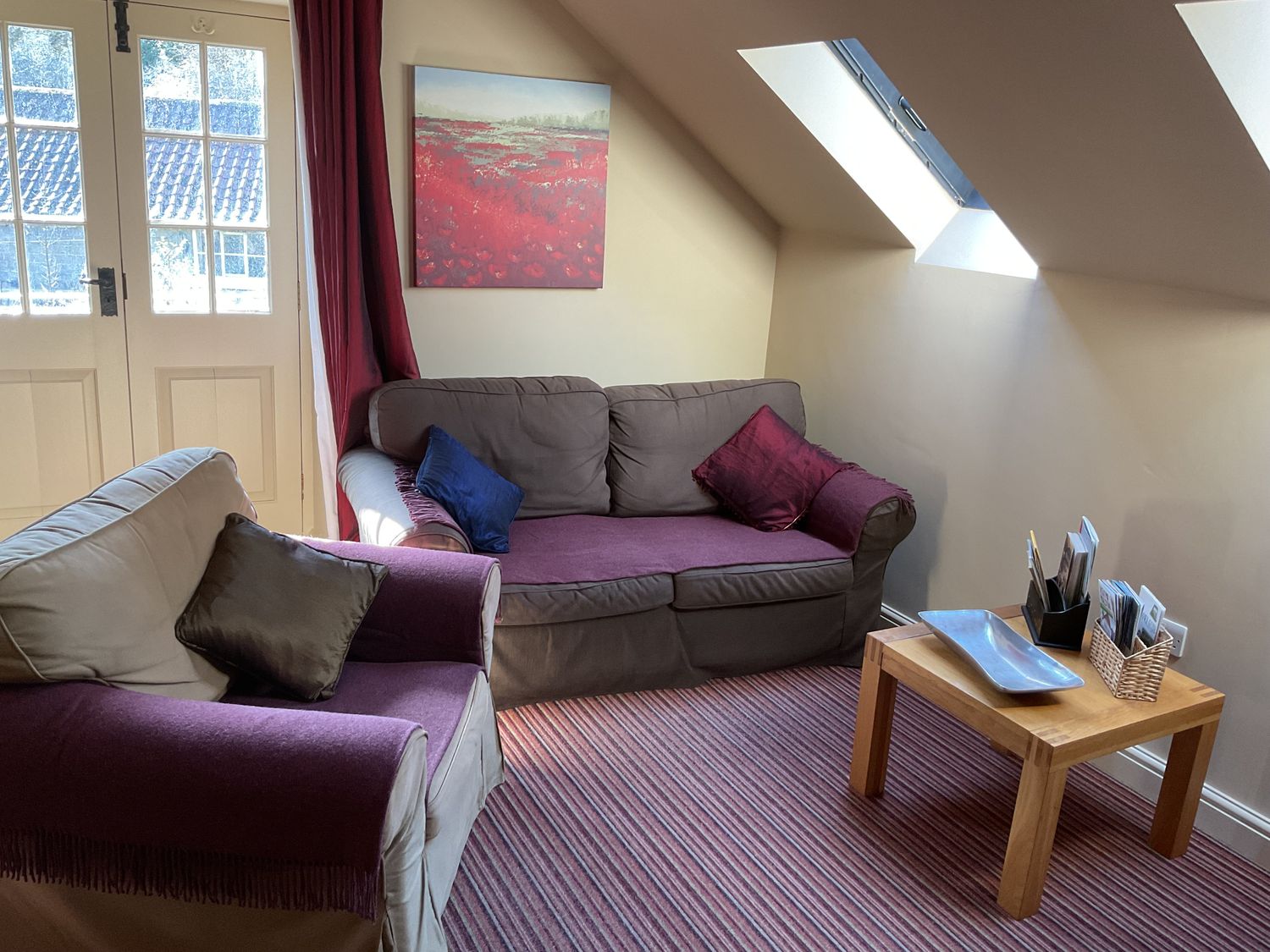 A sitting area with two couches, a wooden table, a window, and a painting at The Hayloft in Lastingham
