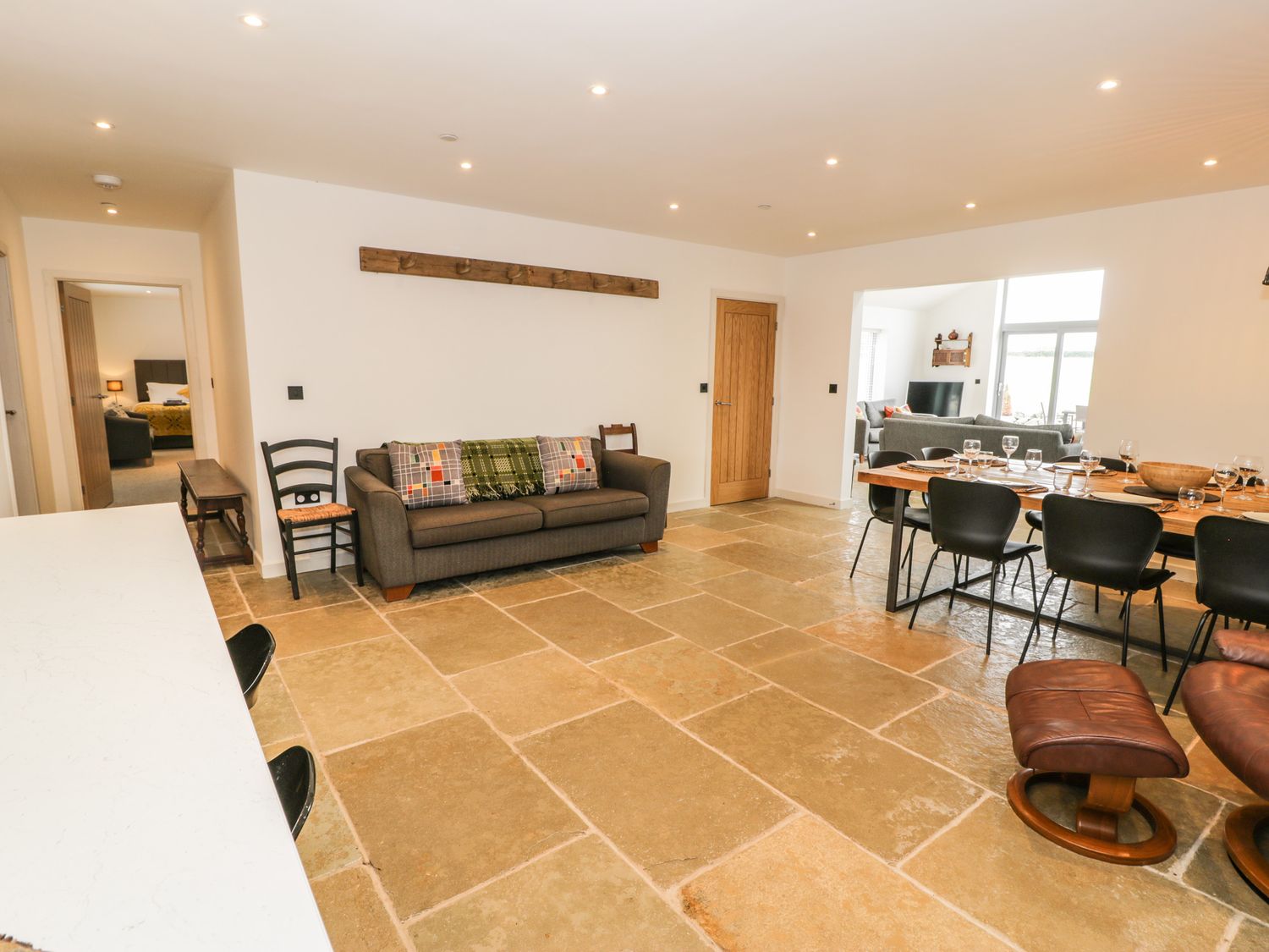 An open living and dining area with a sofa chairs and a dining table set at Cae Sam in Pentraeth