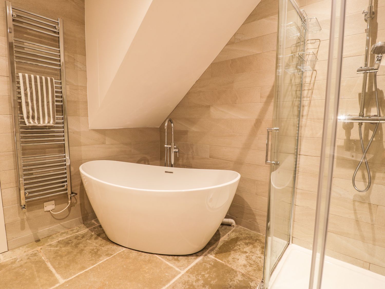 A bathroom with a freestanding bathtub towel rack and glass shower enclosure at Cae Sam in Pentraeth