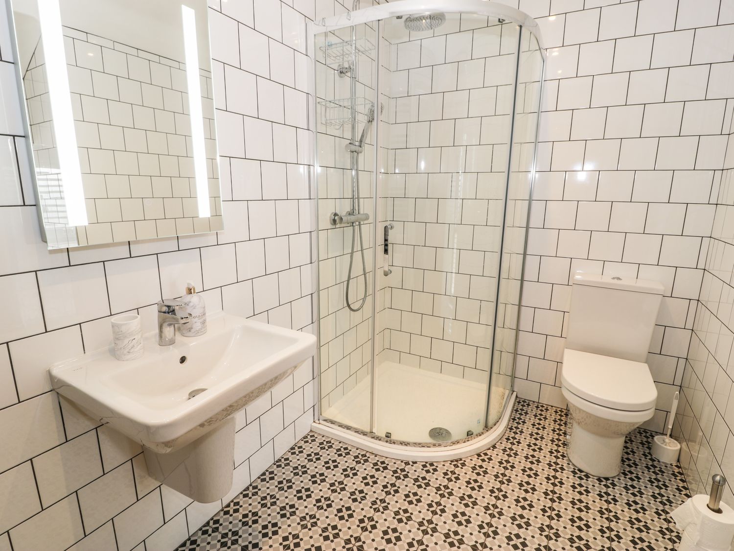 A bathroom with a shower enclosure a toilet a sink and a mirror at Cae Sam in Pentraeth
