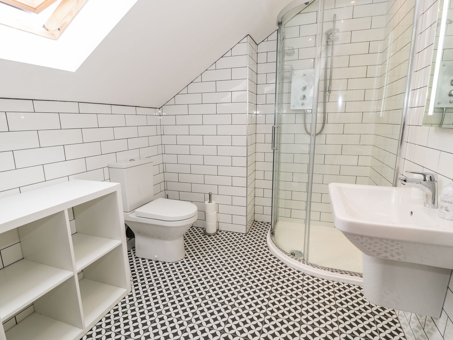 A bathroom with a toilet sink shower cabinet and patterned floor tiles at Cae Sam in Pentraeth